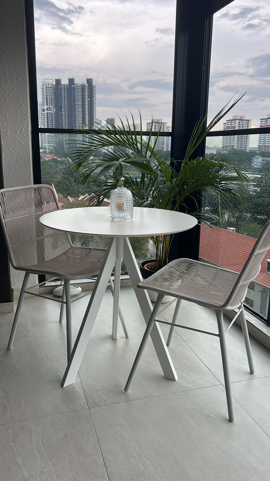 a place to call home finally - Modern patio furniture, white round table, gray wicker chairs, potted plant, cityscape view