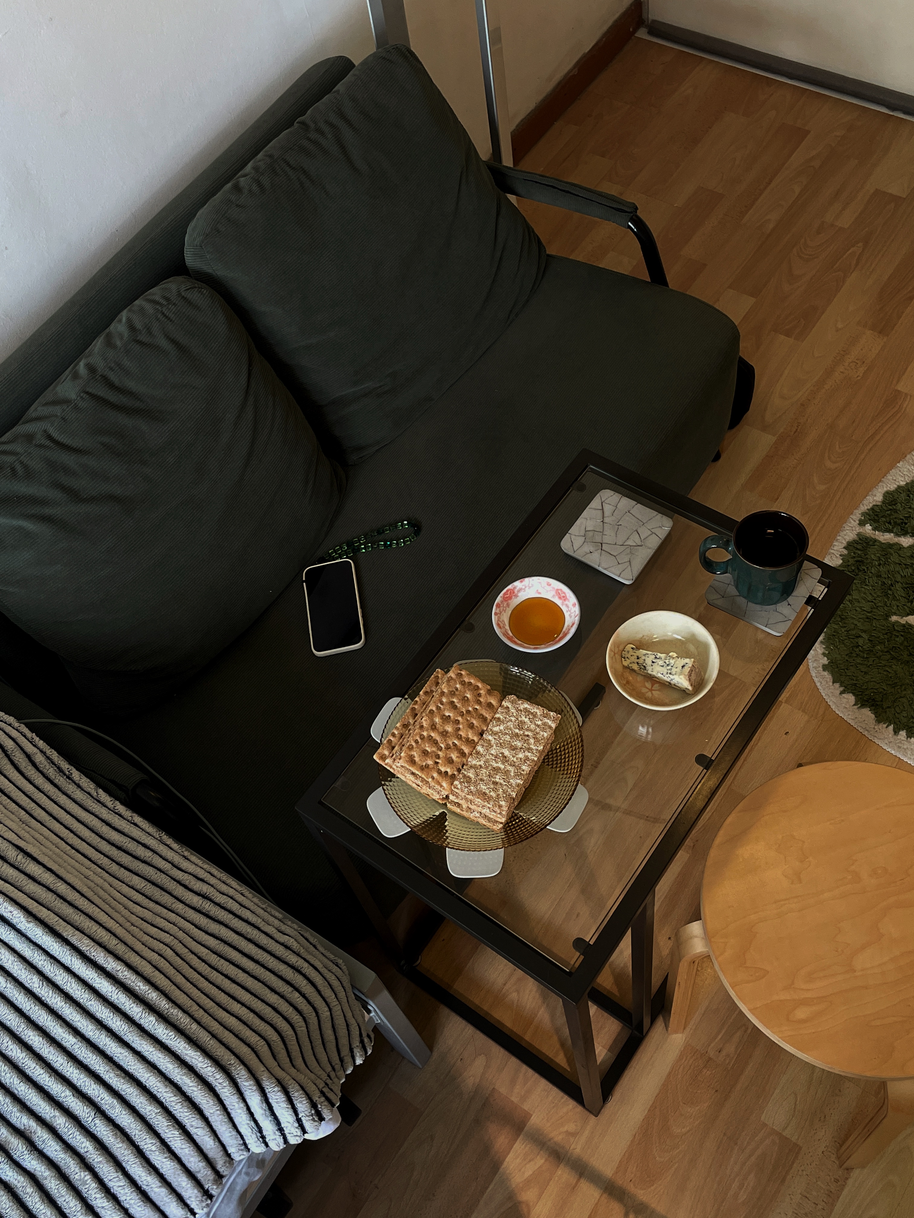 Dining in a Tiny Bedroom - glass coffee table, cozy living room, modern furniture, dark green sofa, wooden floor, striped
