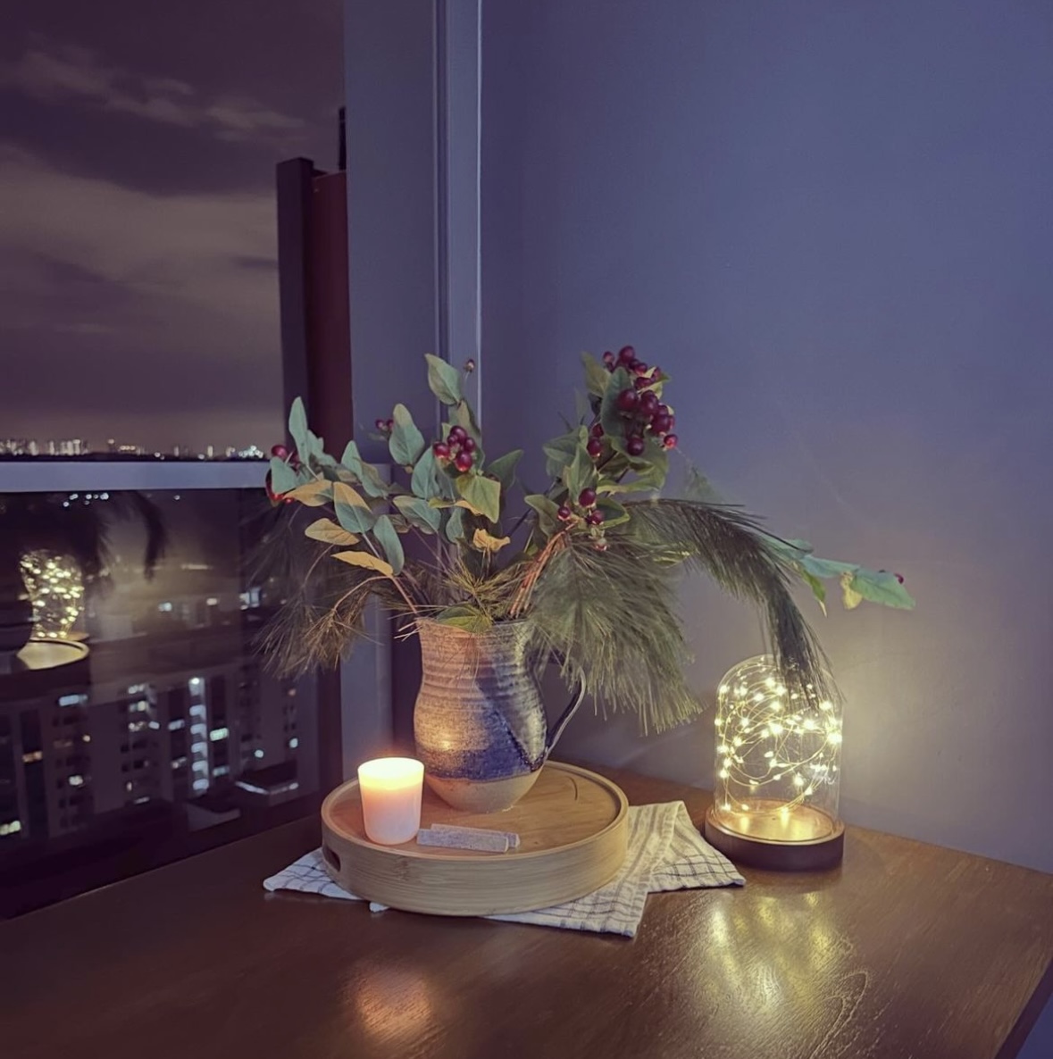 Dining on the balcony: what you need to know  - vase with greenery and berries, candle on wooden tray, cityscape view through