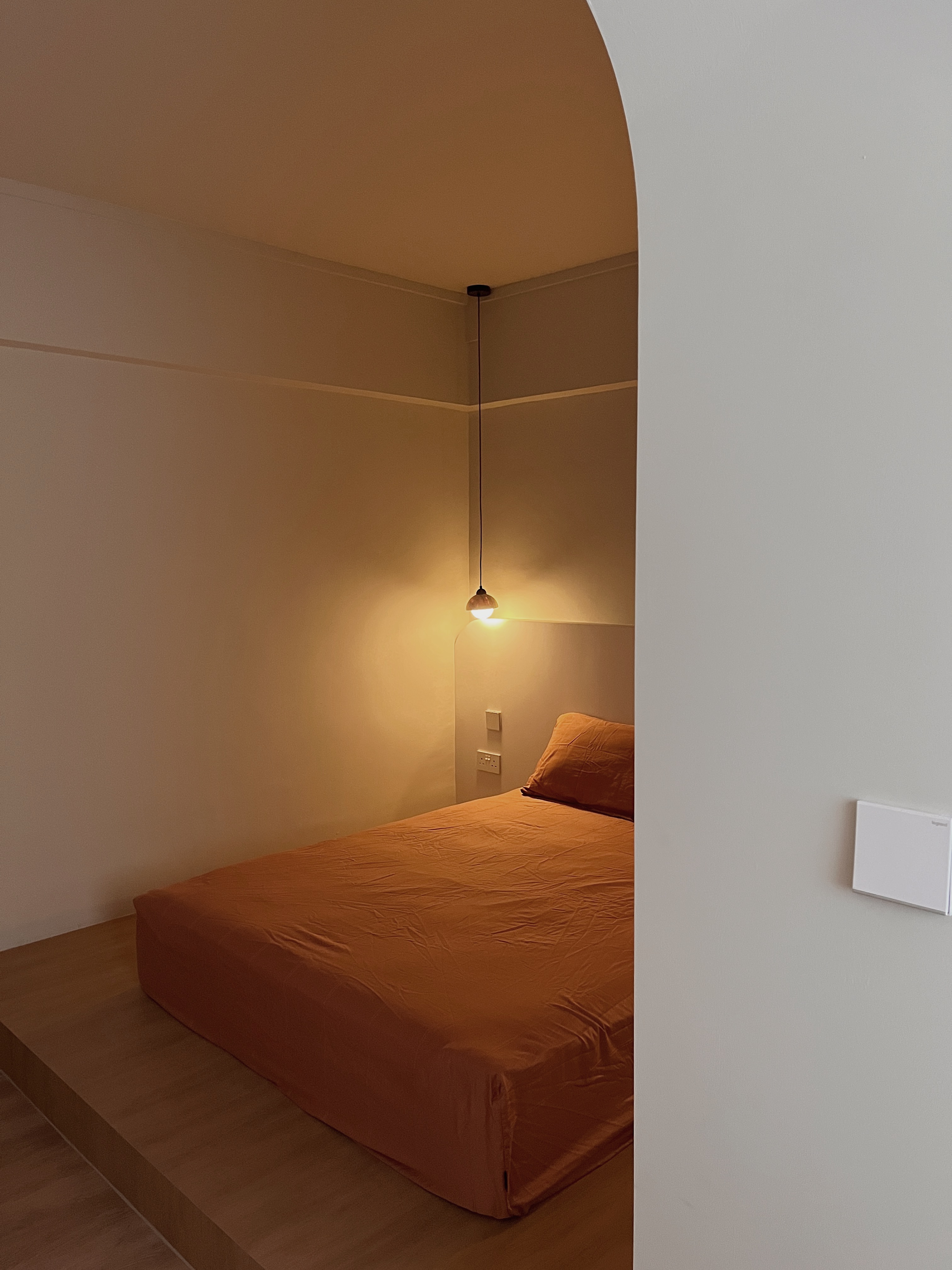 A calm and cosy space - Modern minimalist bedroom, cozy bed, orange comforter, white pillows, warm lighting, simple decor