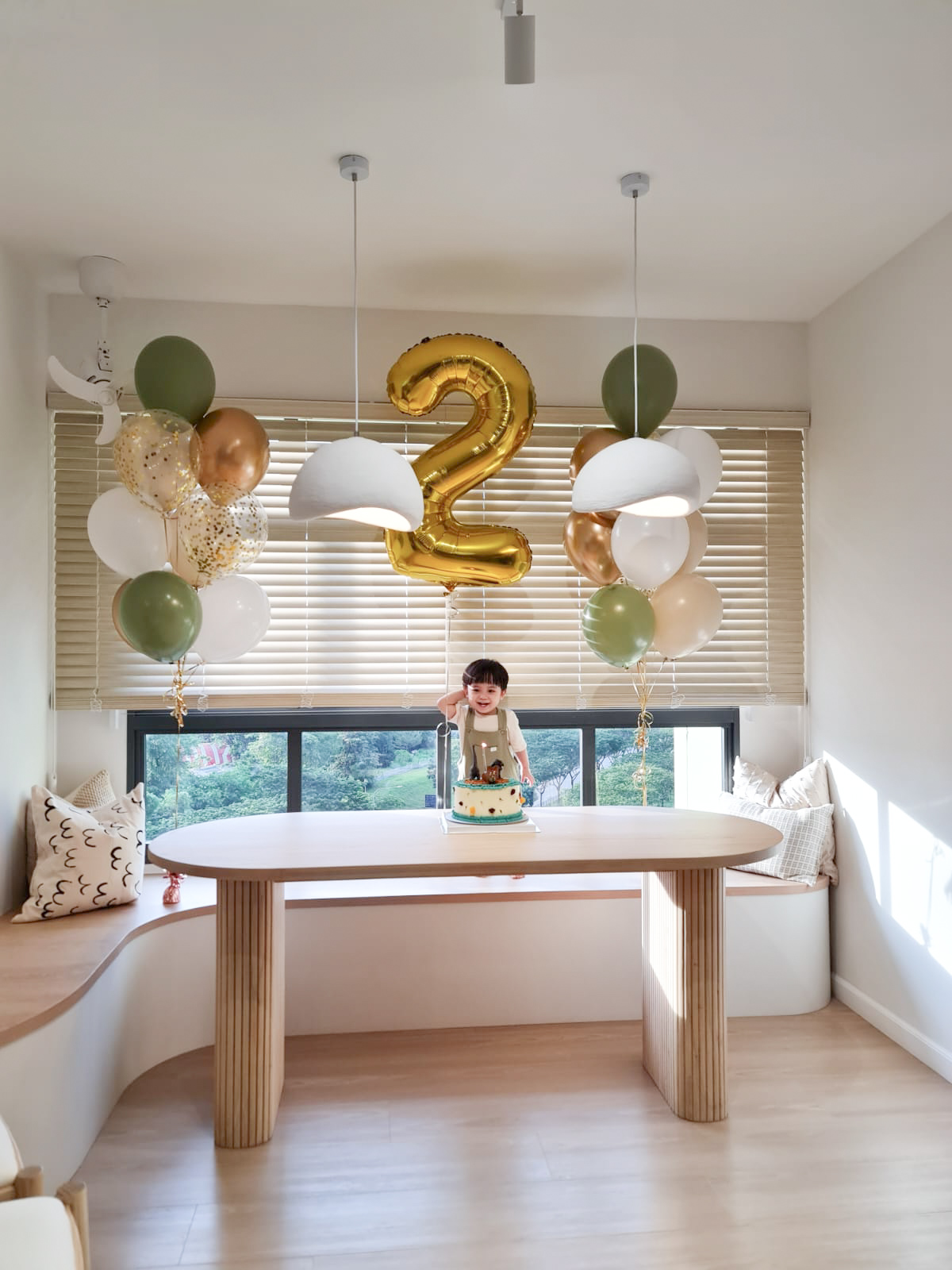 Dining Space - Embracing The Curves  - Modern room with large window, green and gold balloons, white and gold chandelier