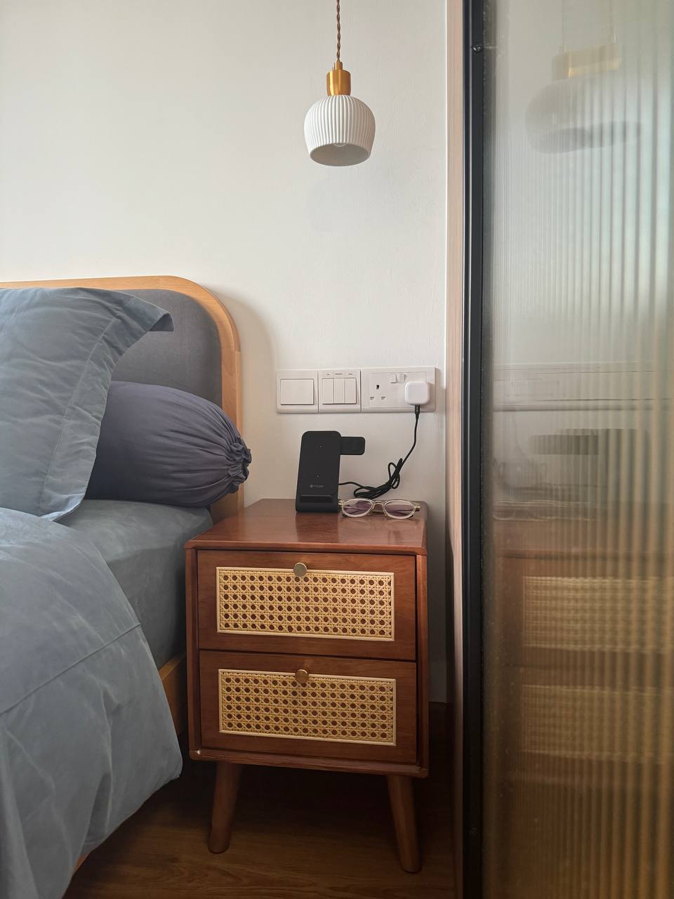 Reimagining Relaxation: Our Home Staycay - Wooden nightstand, gray bed, blue pillows, woven design, wooden drawer, bedside