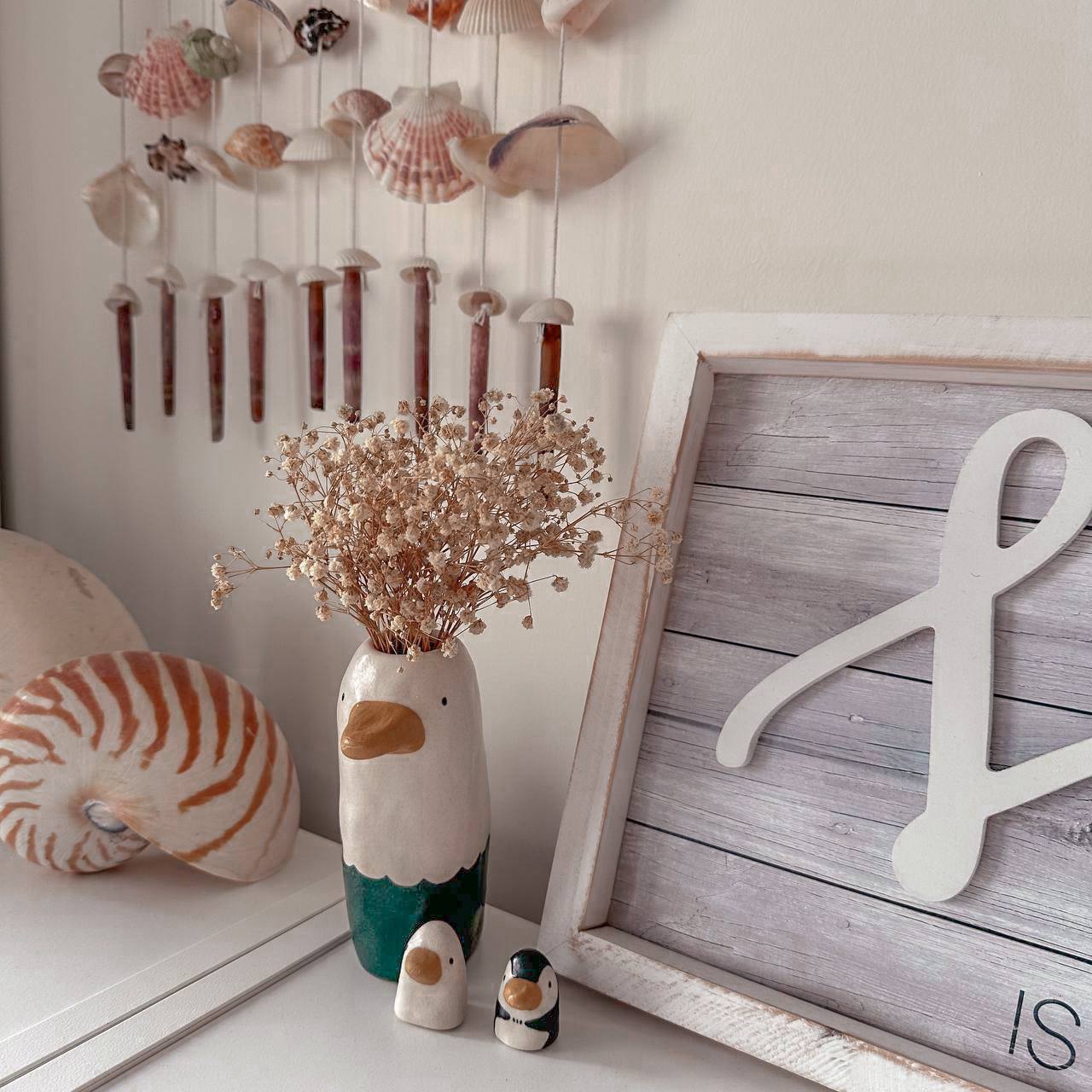 Beach Inspired Dining Space - vase with seashells, wooden wall art, penguin figurine, driftwood, driftwood decoration, rustic