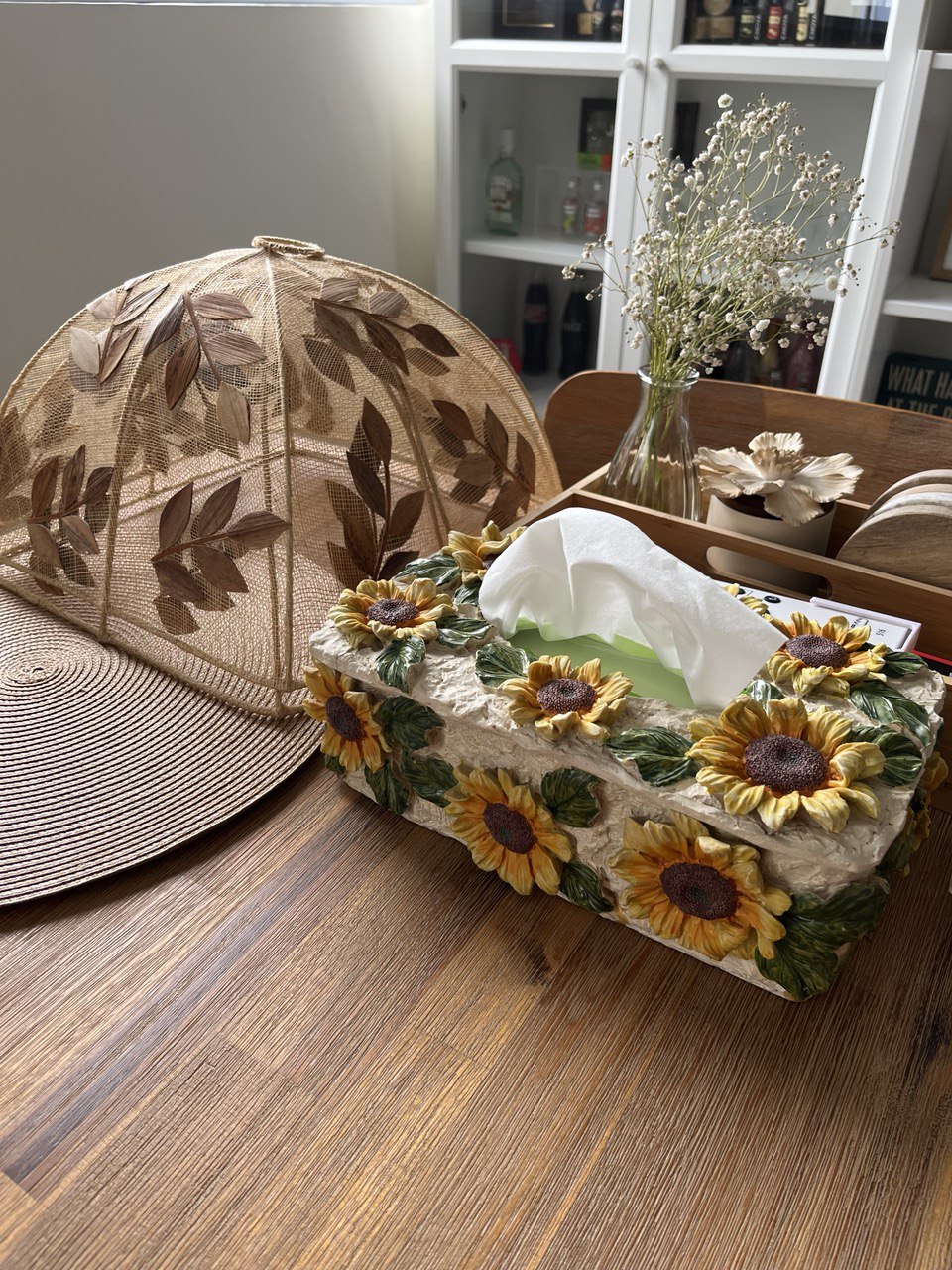 Beach Inspired Dining Space - Sunflower-patterned box, woven umbrella, natural wood table, vintage vase, dried flowers