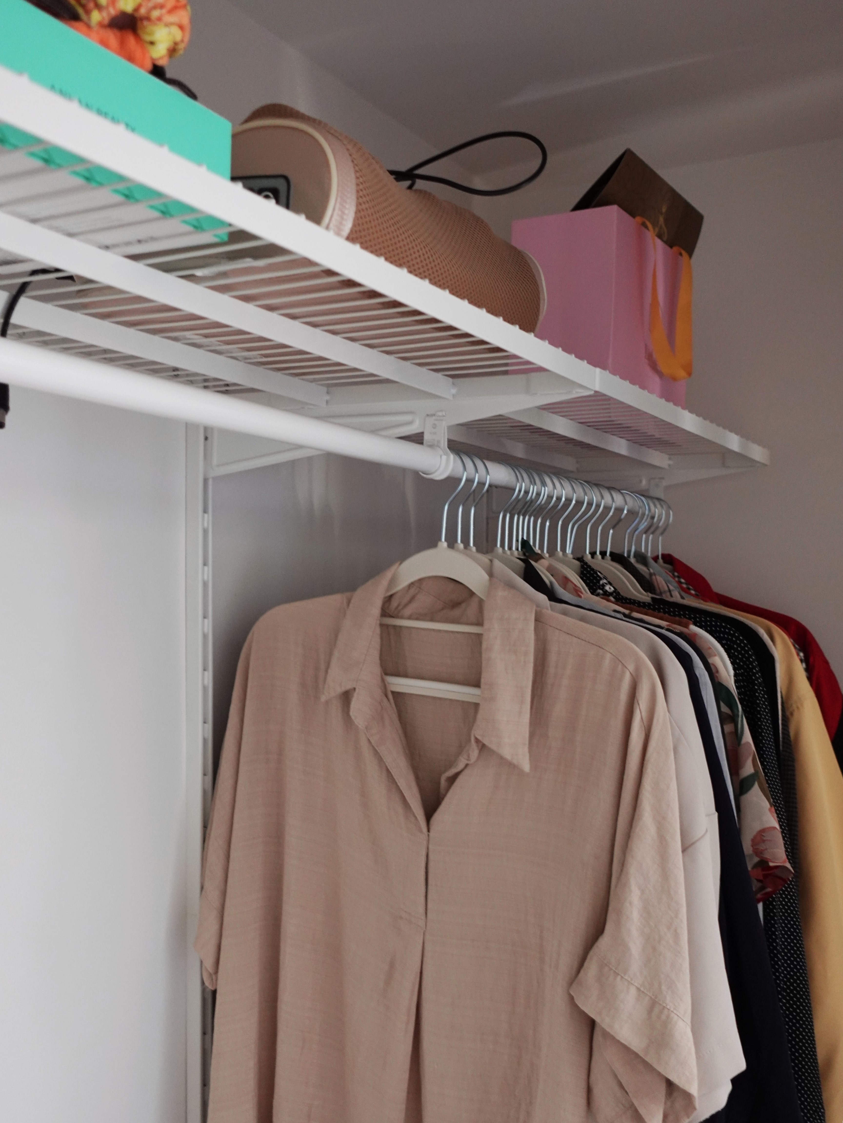 A minimal bedroom with a wardrobe that you’ve never seen before - Organized closet with neatly hung beige shirt, various