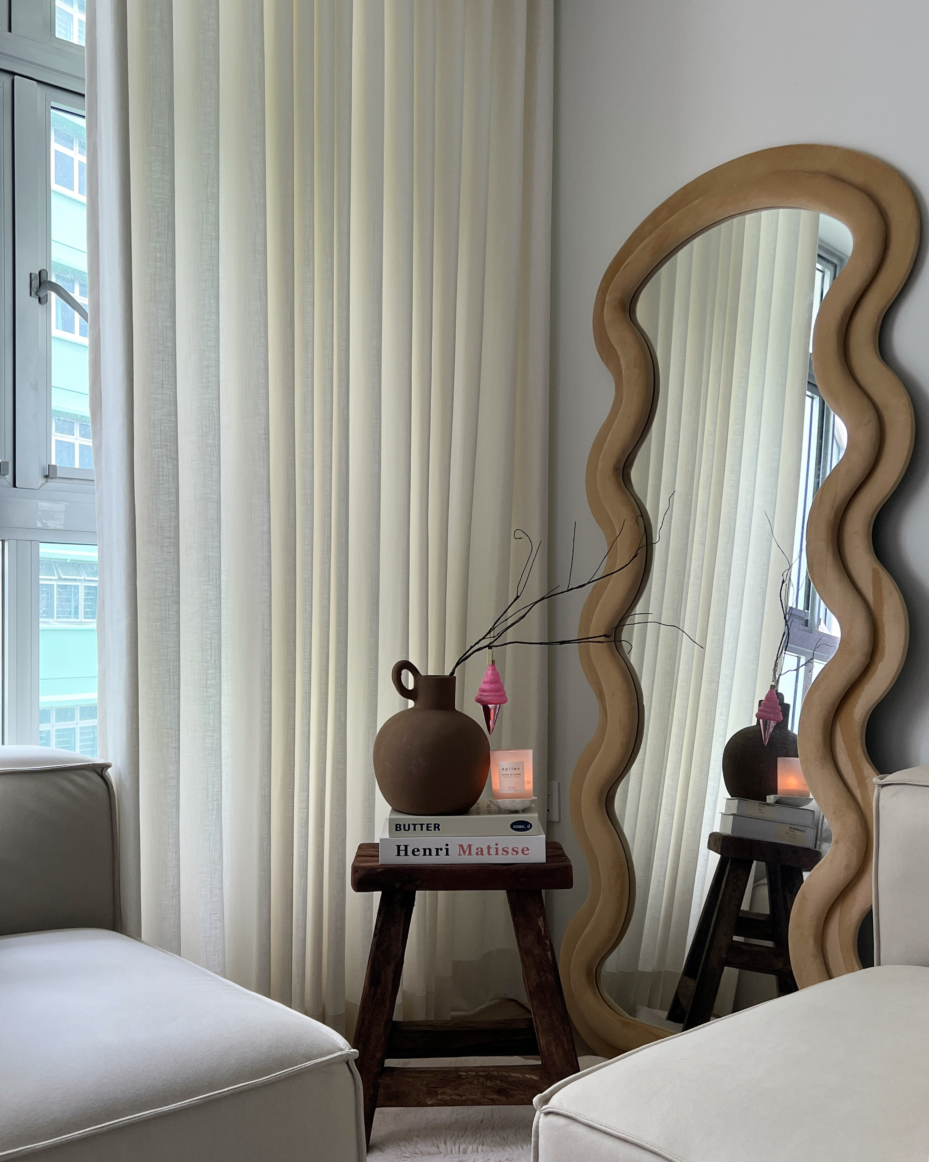 Some home decor tips! - Cream-colored curtains, soft natural light, modern decor, wavy mirror frame, brown ceramic vase, pink