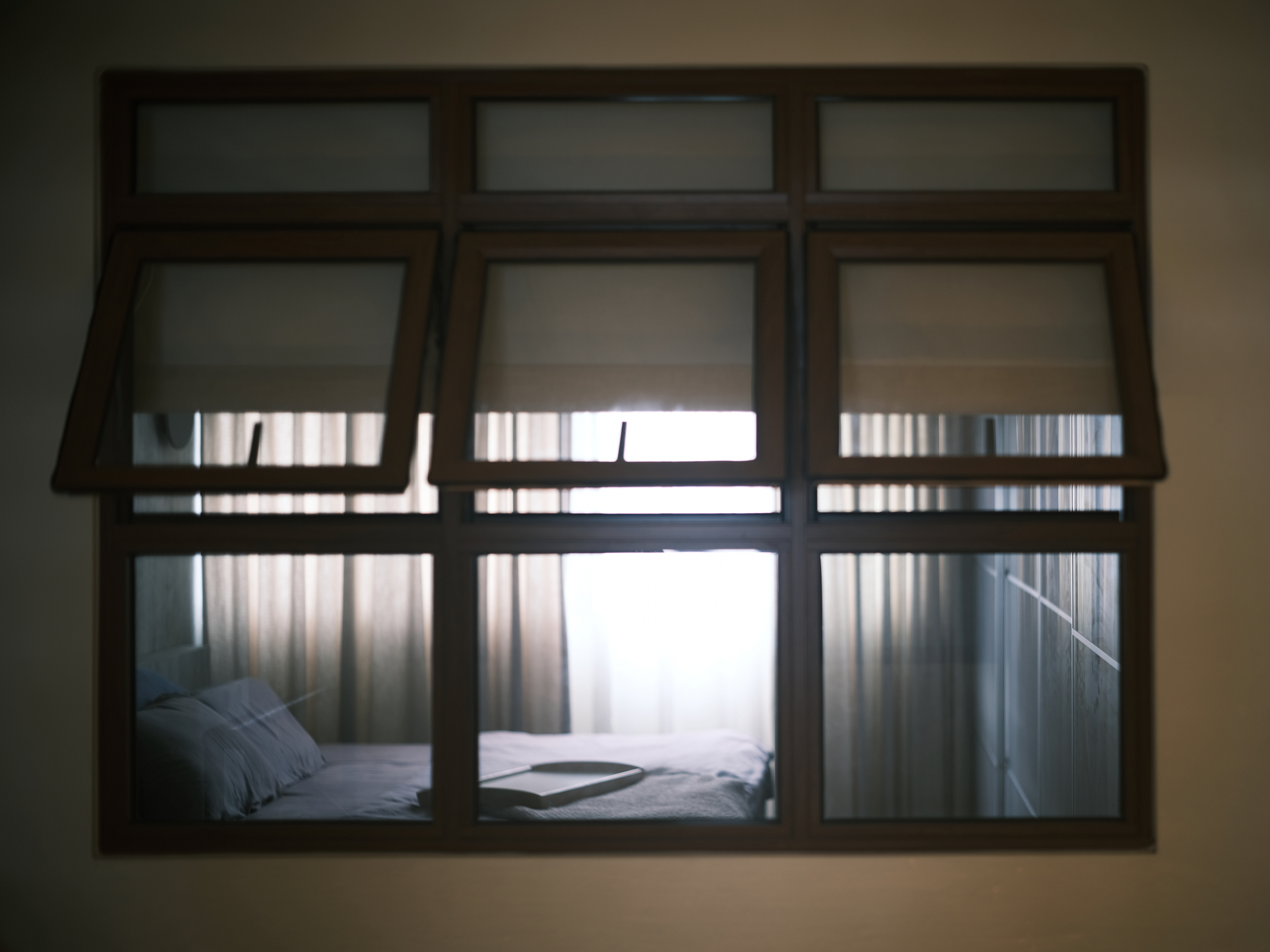 A Japanese-inspired cave-like bedroom retreat - Window with blinds, light filtering through, wooden frame, interior view, bed