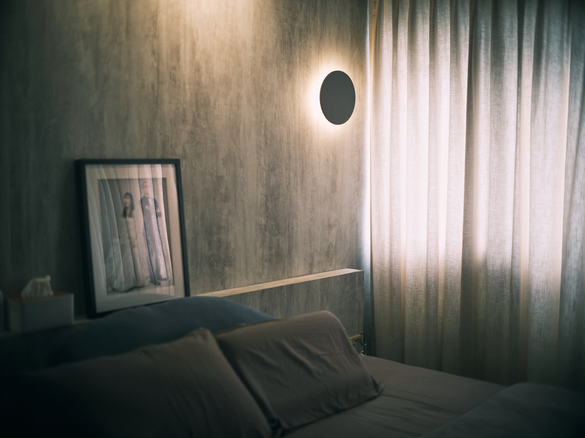 A Japanese-inspired cave-like bedroom retreat - Modern minimalist bedroom, soft lighting, textured gray wall, framed