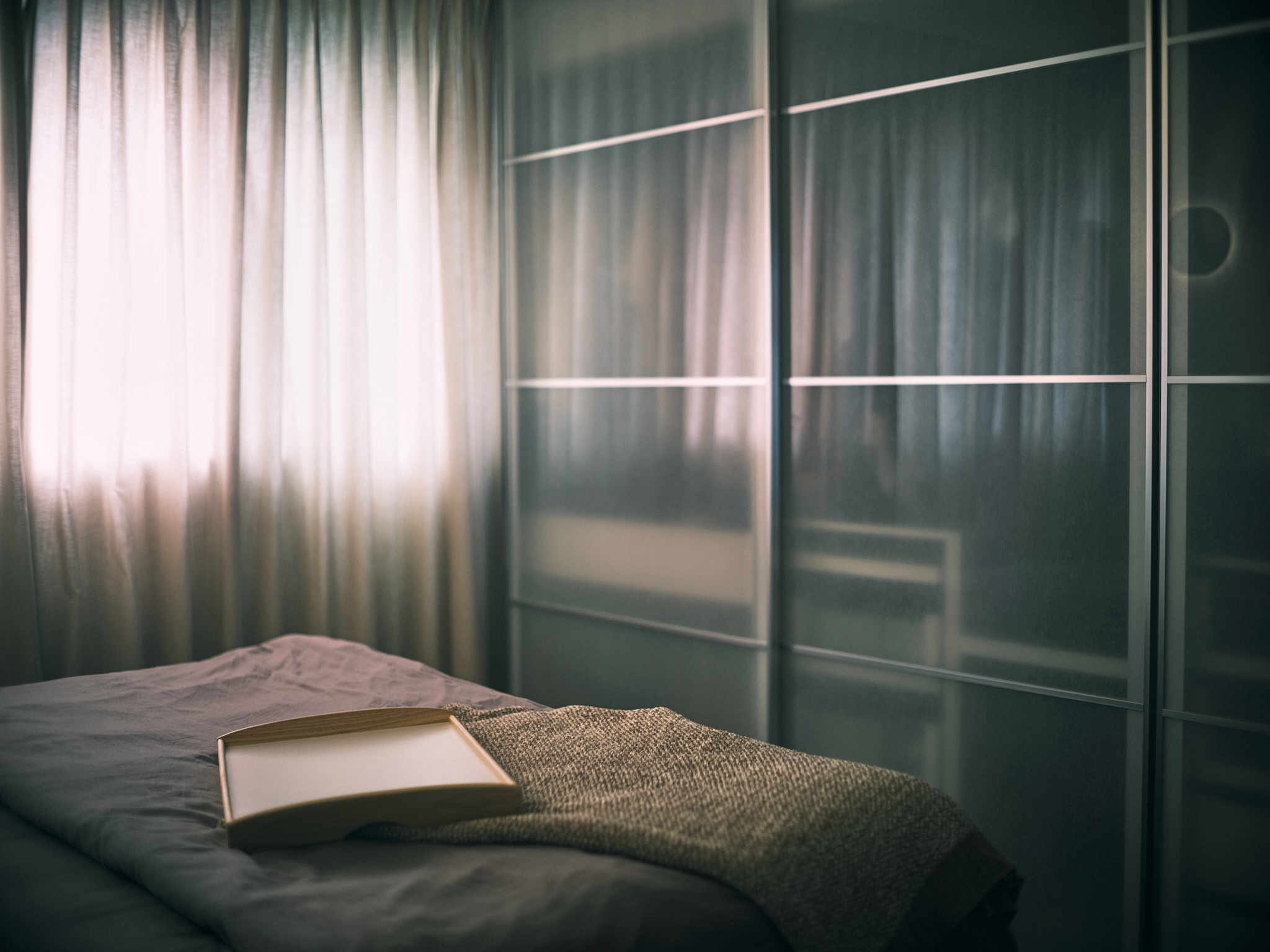 A Japanese-inspired cave-like bedroom retreat - Soft, diffused light filters through sheer curtains, casting gentle shadows