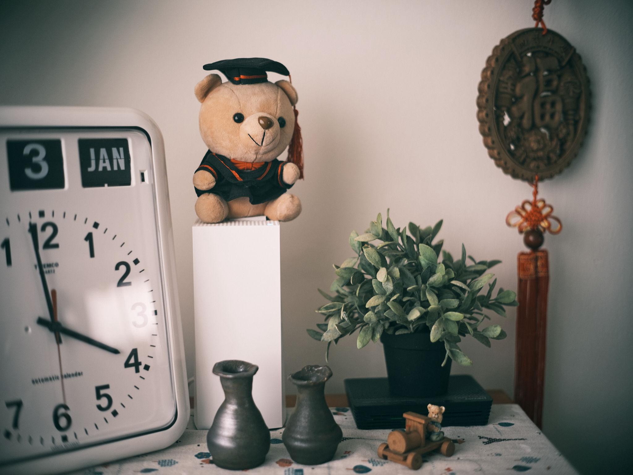 A proud faux plant owner - 3, Jan, teddy bear, graduation cap, clock, potted plant, small figurine, ceramic vase, wooden toy