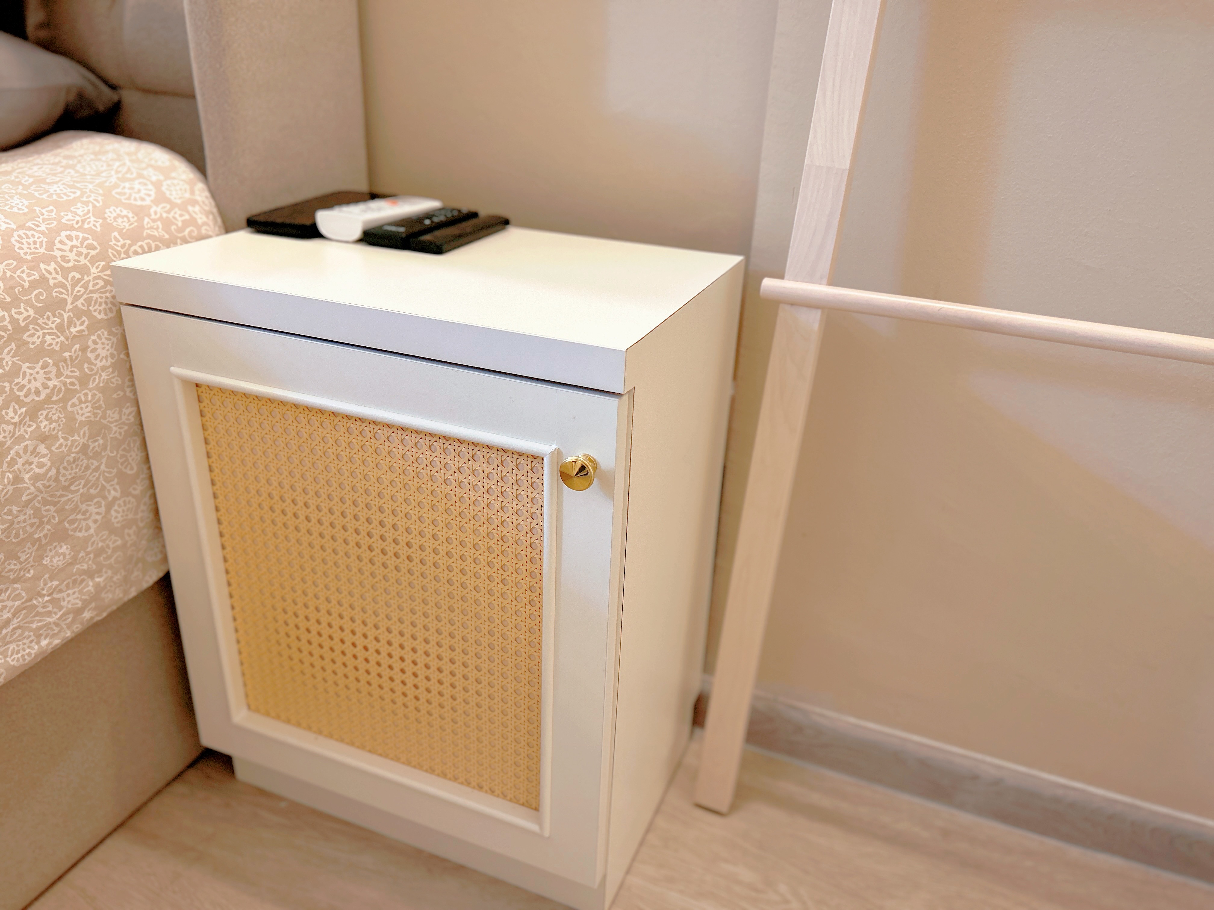 Welcome to our tranquil bedroom sanctuary, where relaxation awaits! - White nightstand with yellow mesh front, beige