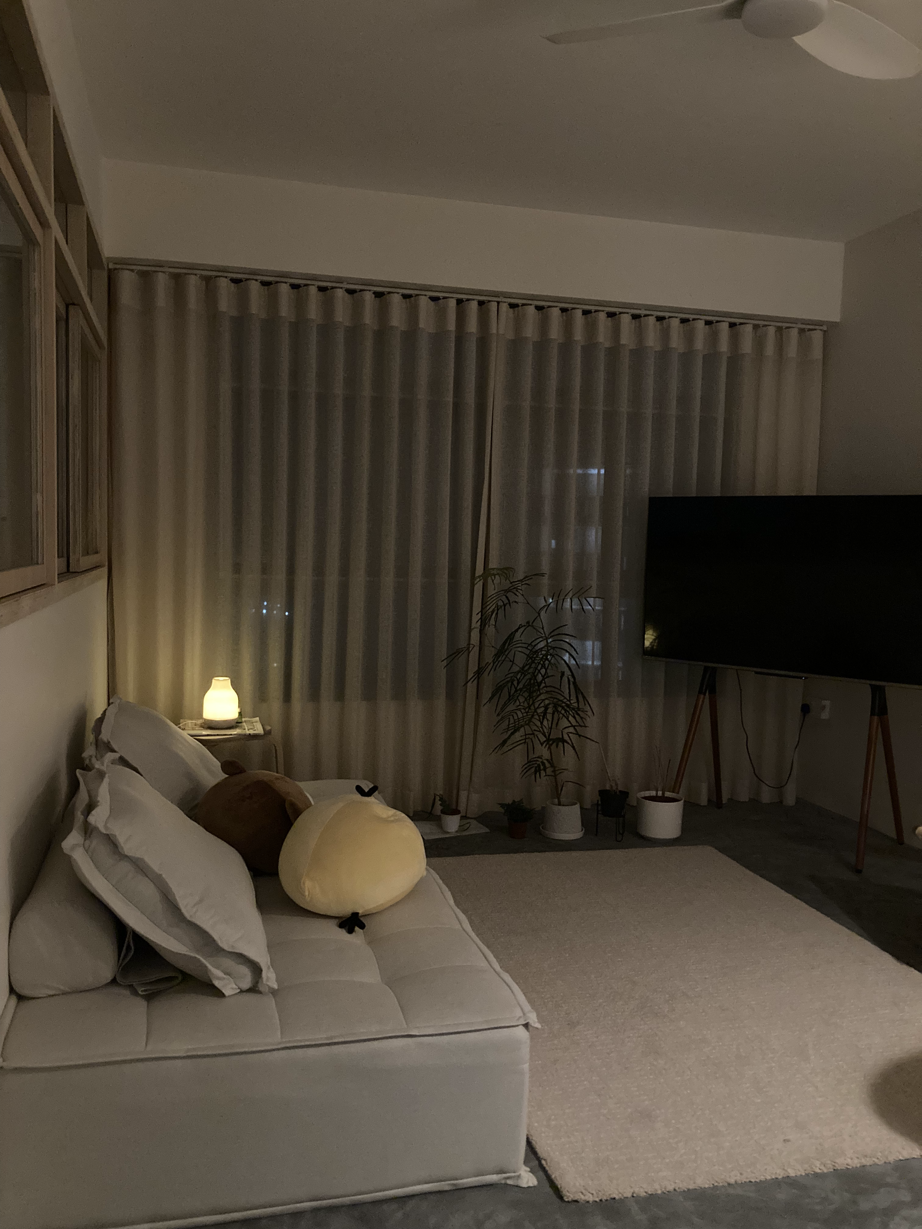 Living room transformed with mood lighting - dimly lit room, cozy living space, comfortable sofa, plush pillows, soft