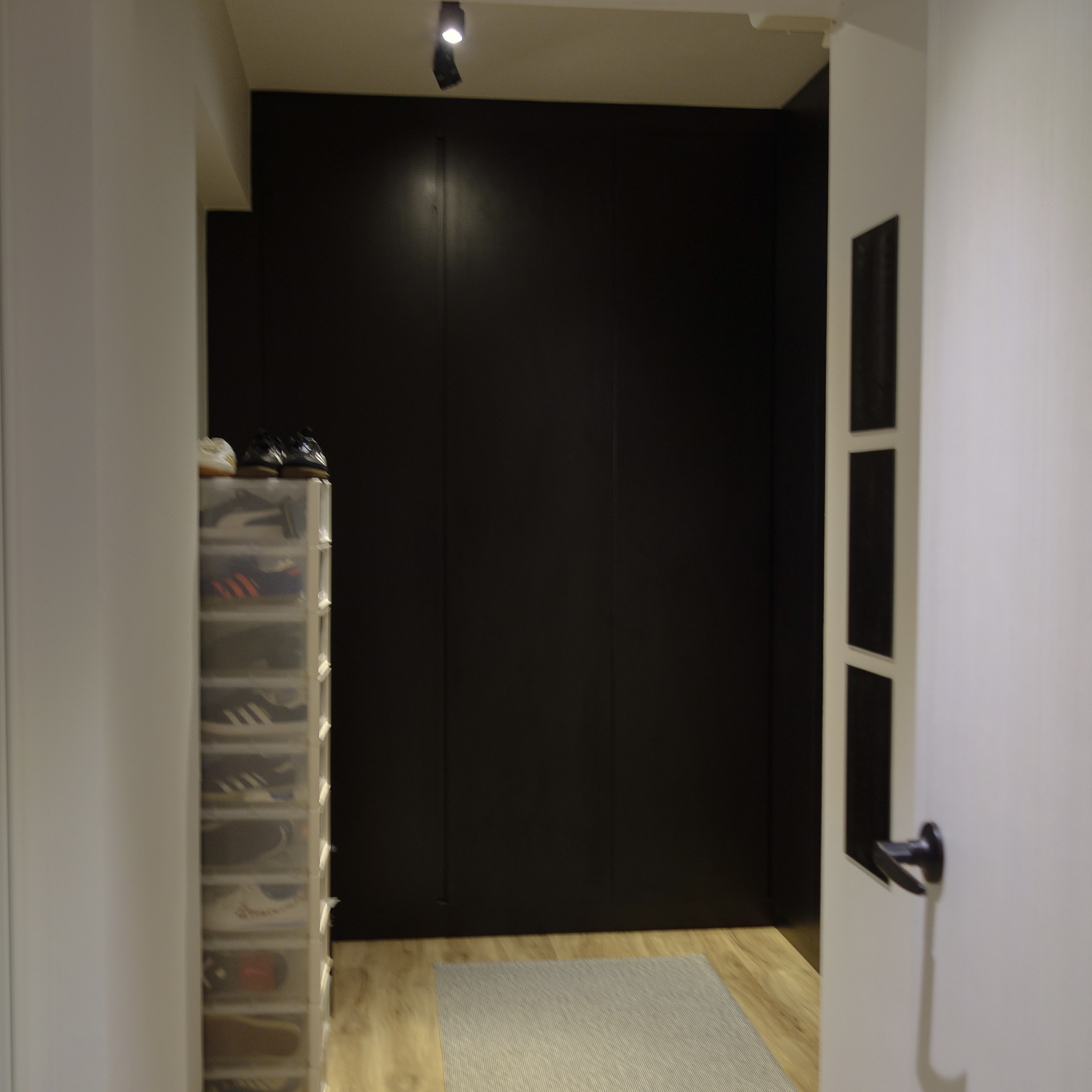 A cozy retreat: The master bedroom - Shelf with shoes, black storage cabinet, white door handle, wooden floor, light fixture