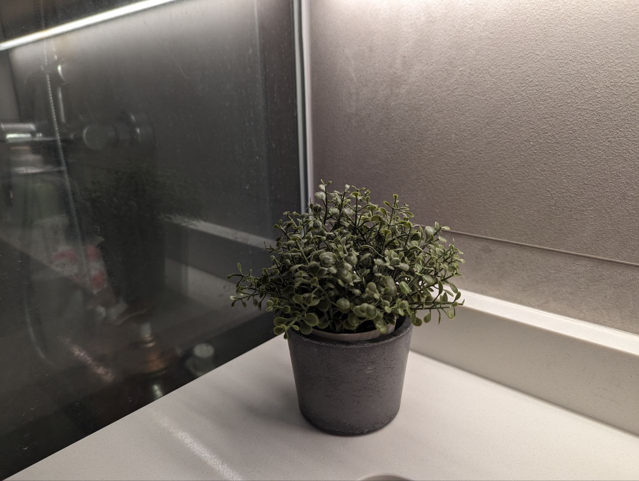 Fake it till you make it: Artificial Plants Everywhere - Small green potted plant on kitchen counter, gray textured pot