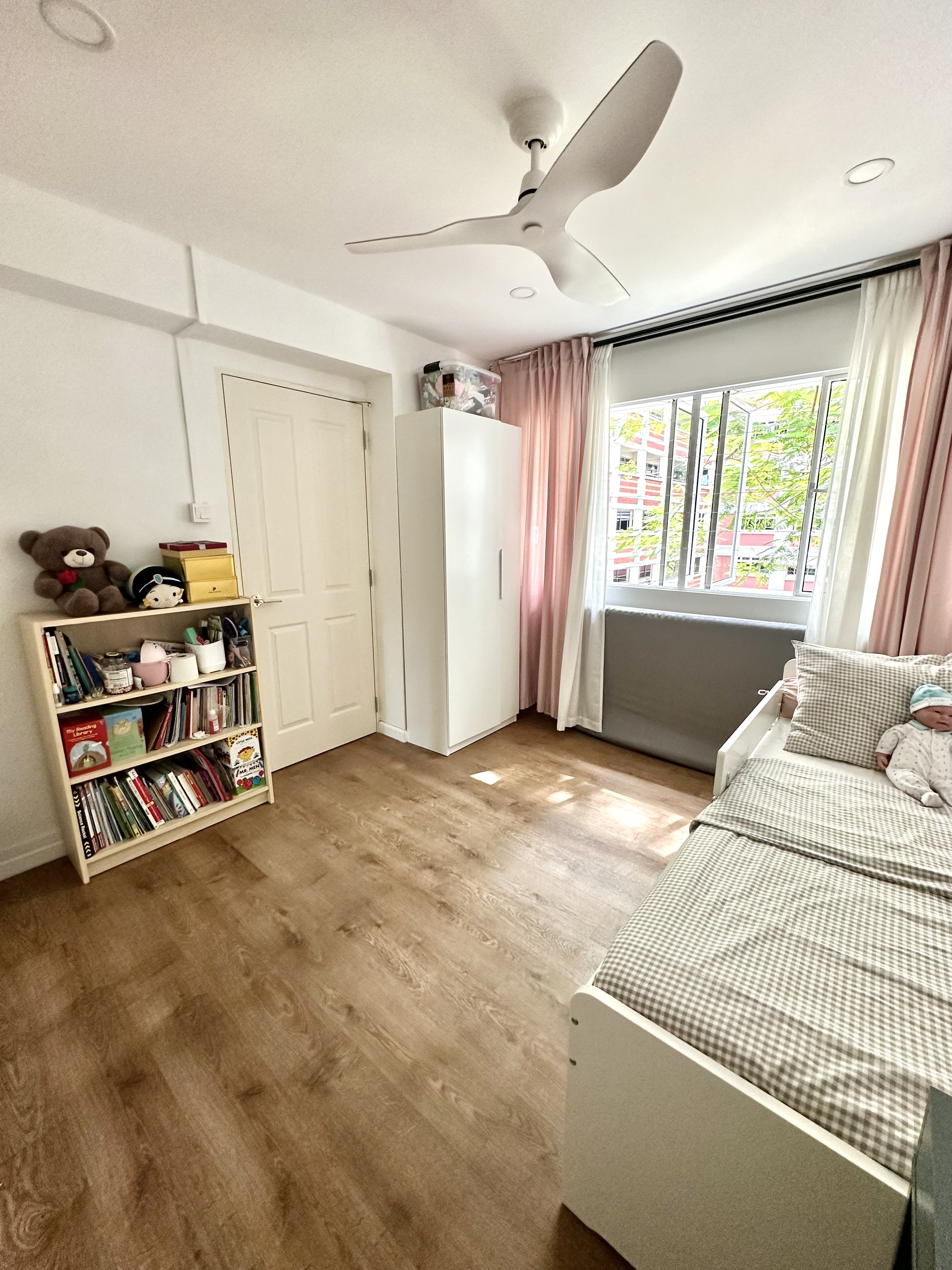 Kid’s Bedroom Makeover!  - Wooden floor, white ceiling, ceiling fan, white door, white wardrobe, pink curtains, baby in bed