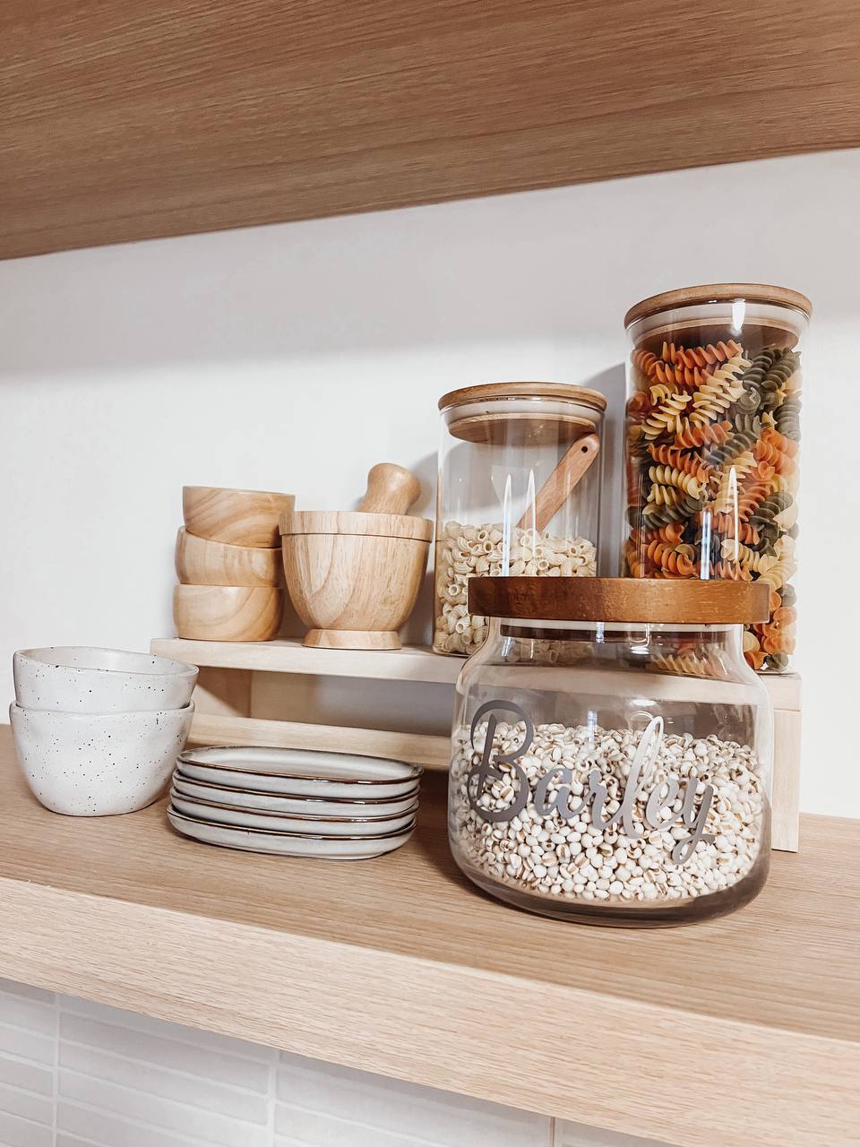 Blu Kitchen - Wooden kitchen shelf, pasta jars, white speckled bowl, wooden cutting board, wooden mortar and pestle, wooden
