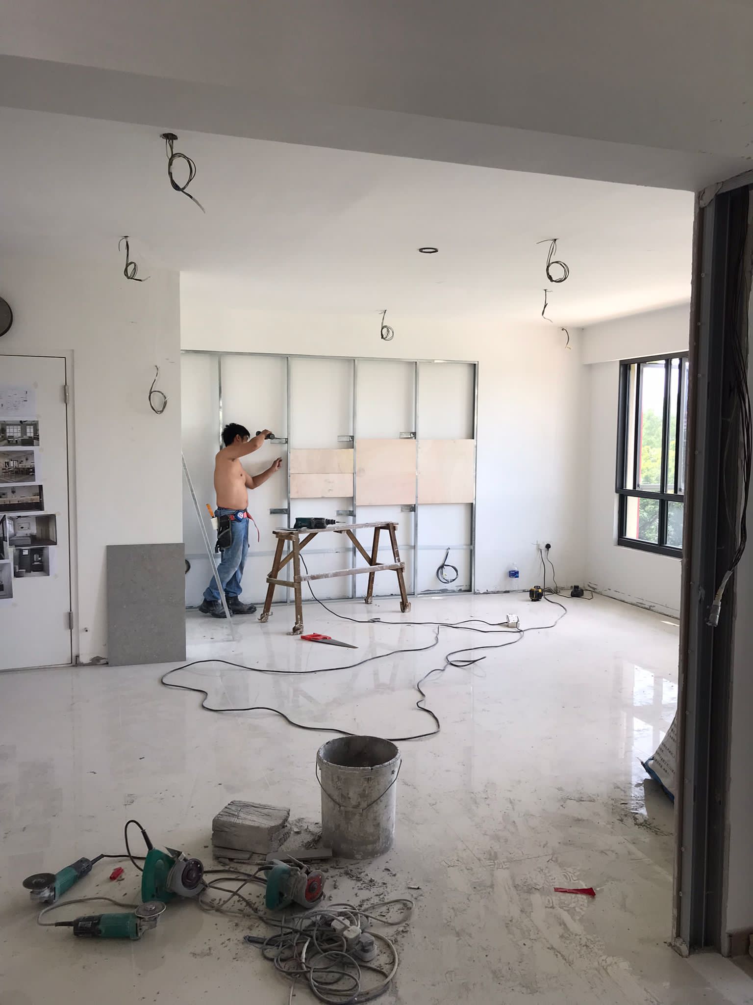 Neutral About Our Living Room - Construction site, barefoot worker, bare-chested man, metal cabinet, white walls, unfinished