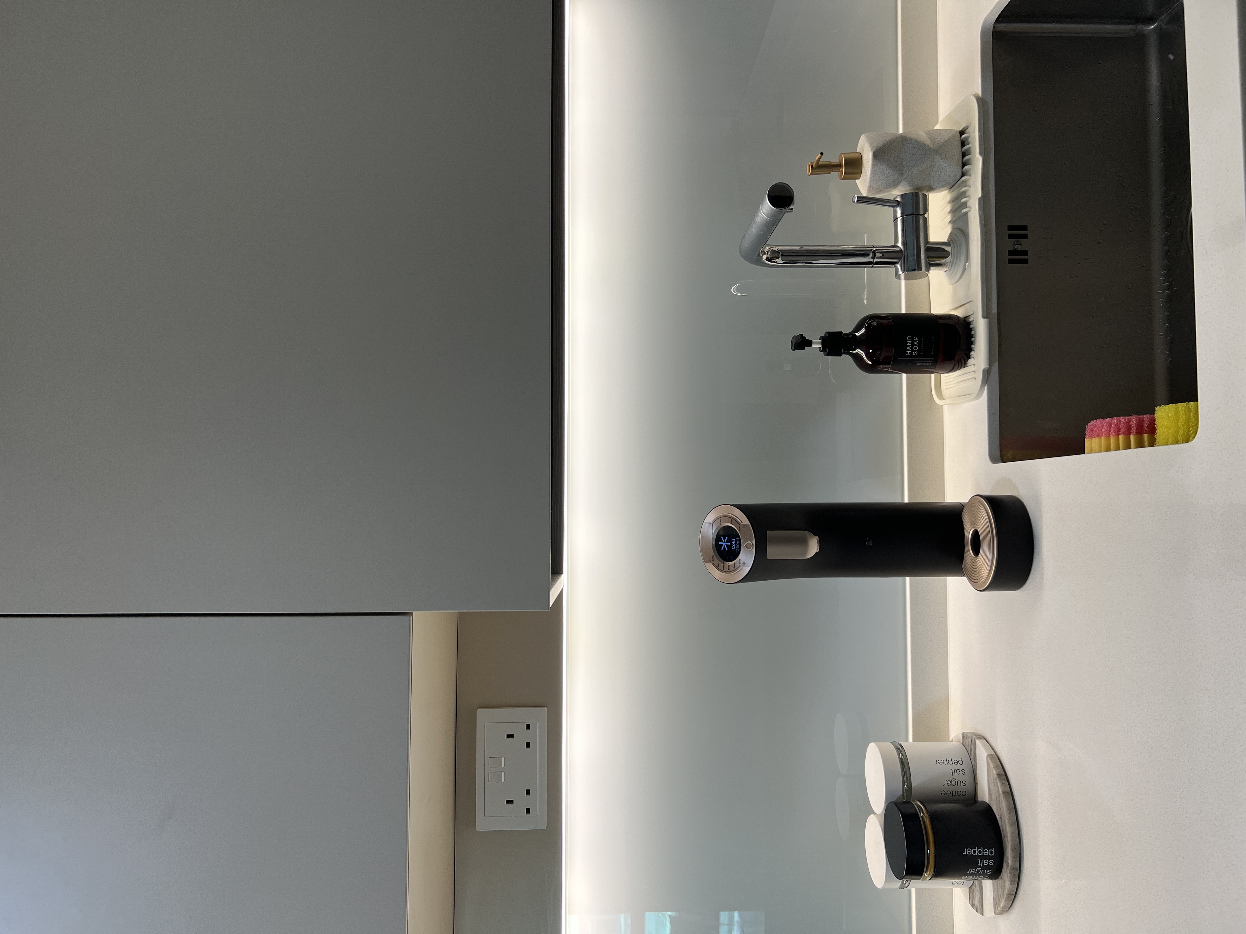 A neutral-minimalist-functional Kitchen - Modern minimalist bathroom, sleek faucet, black soap dispenser, gray cabinets