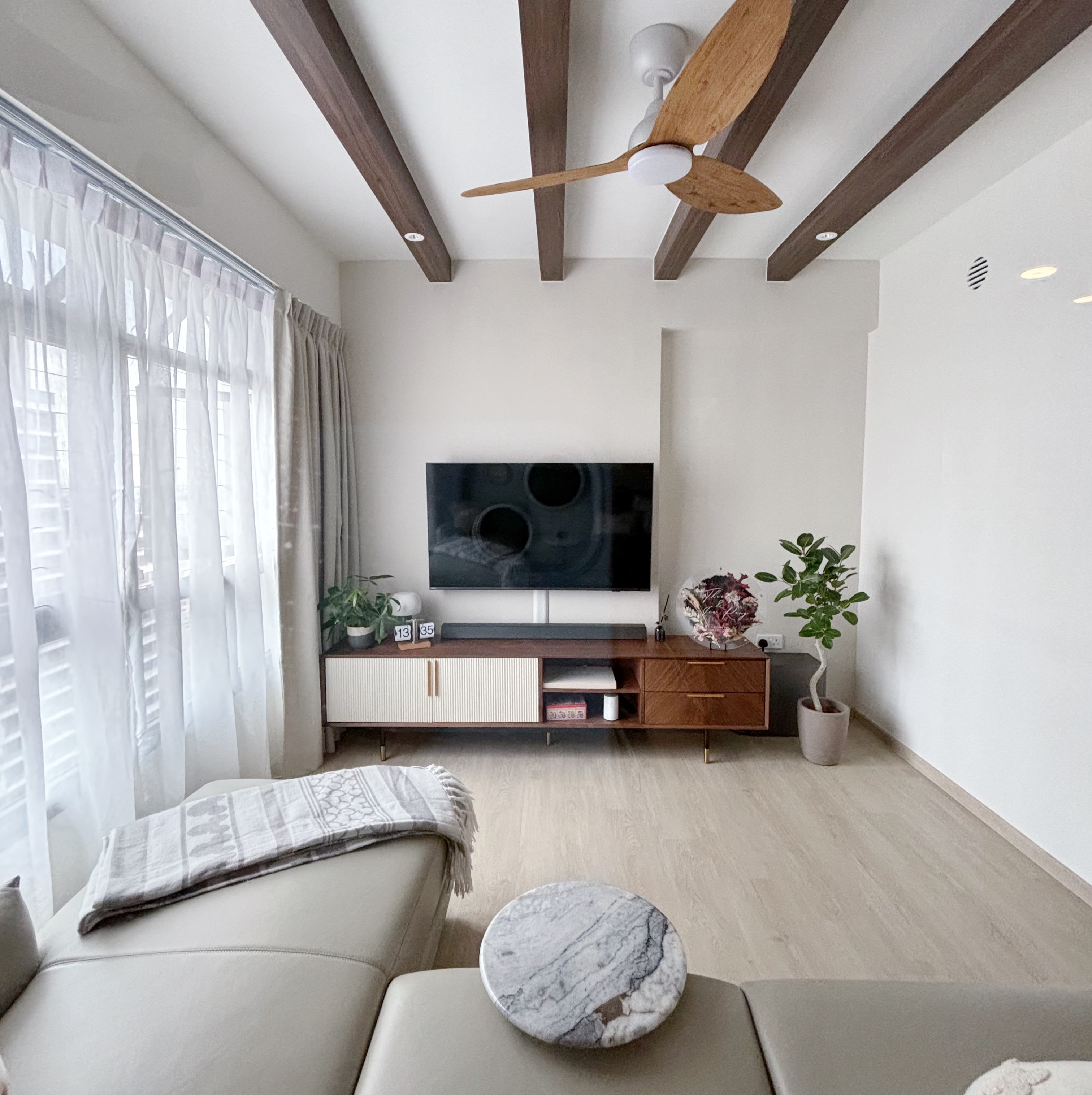 Our Modern Farmhouse Living Room - Modern living room with large window, light beige sofa, marble coffee table, wooden TV