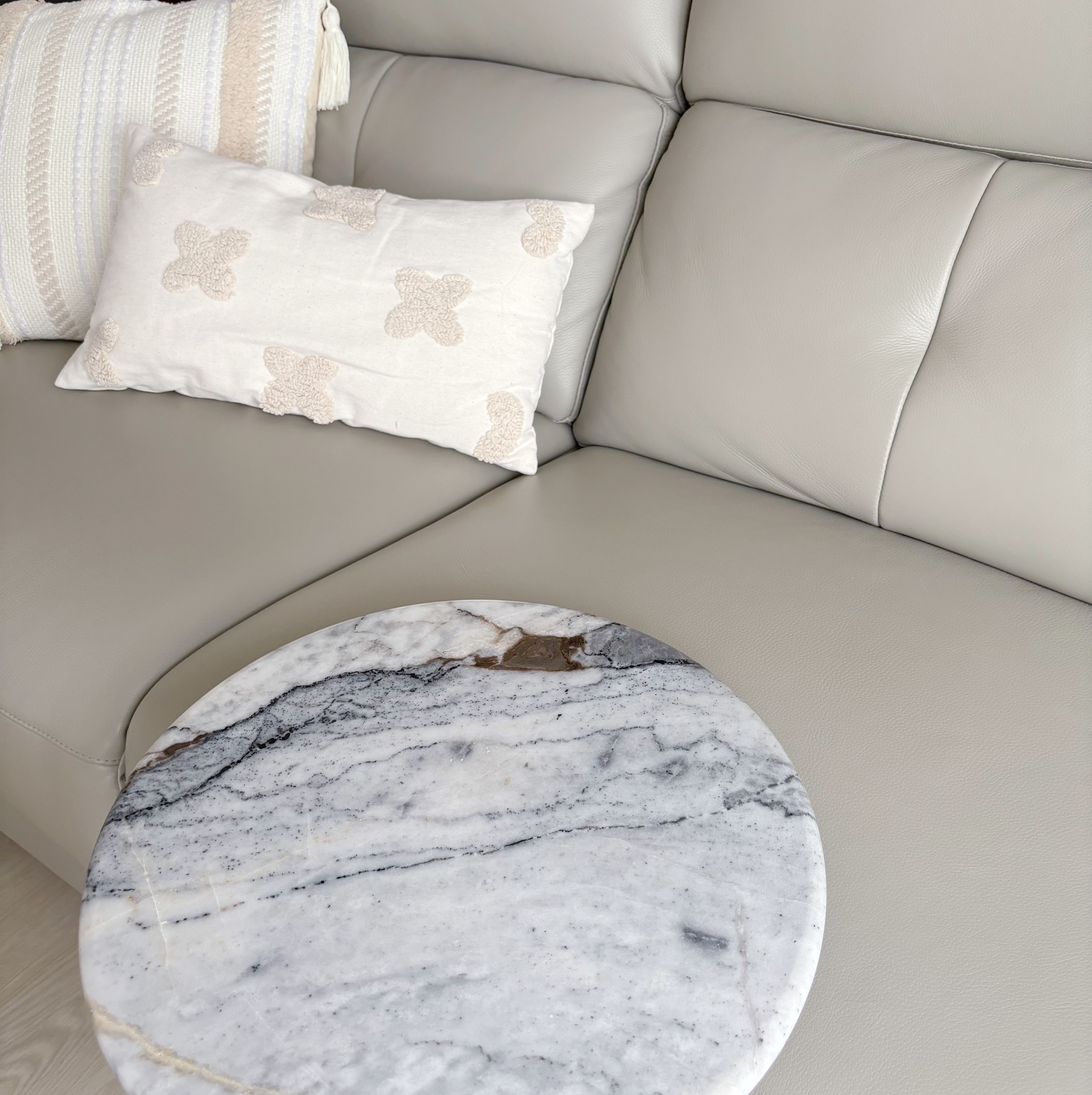 Our Modern Farmhouse Living Room - Cream-colored leather sofa, plush pillows with floral patterns, marble coffee table with