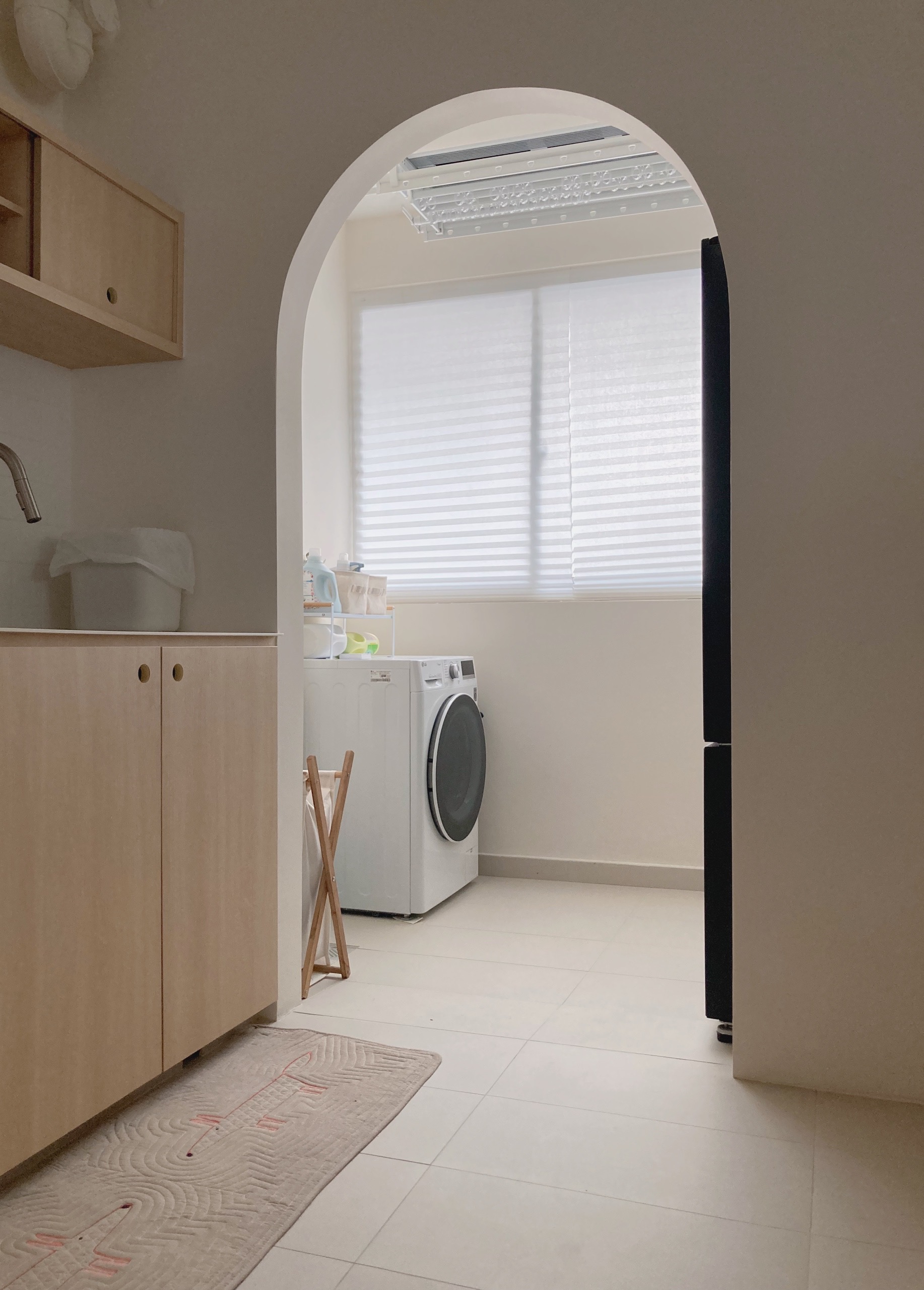 Simple but unconventional open concept kitchen  - Wooden kitchen cabinets, white washing machine, light-colored floor tiles