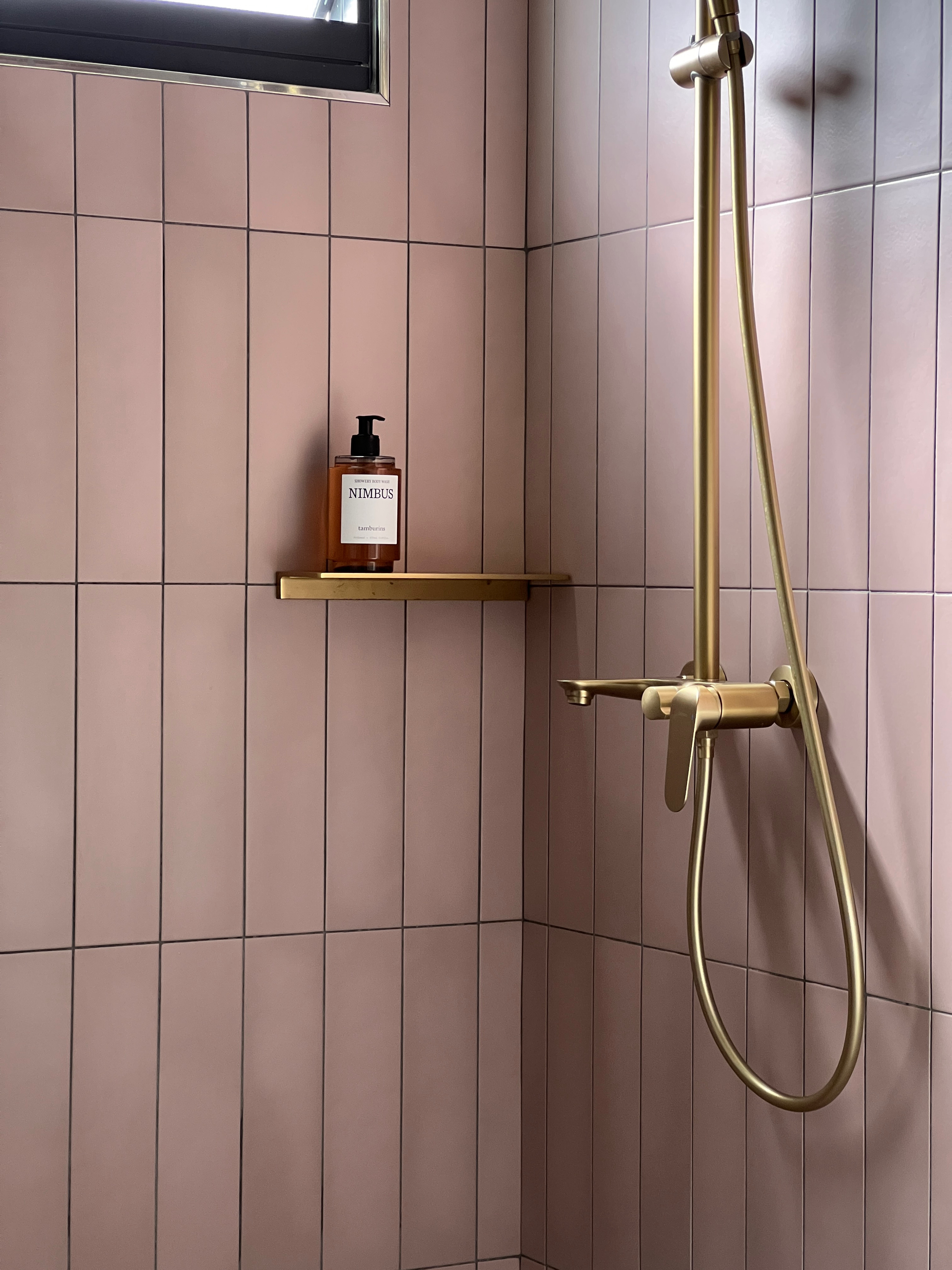 A toilet of texture and character inspired by our visit to Australia - gold shower head, pink tiled wall, modern bathroom