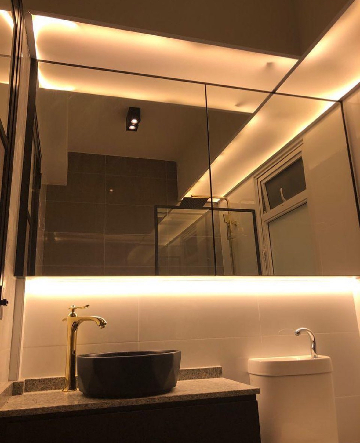 Washroom: Black and gold theme with plants for a relaxing ambiance  - Modern bathroom with sleek design, large mirror and