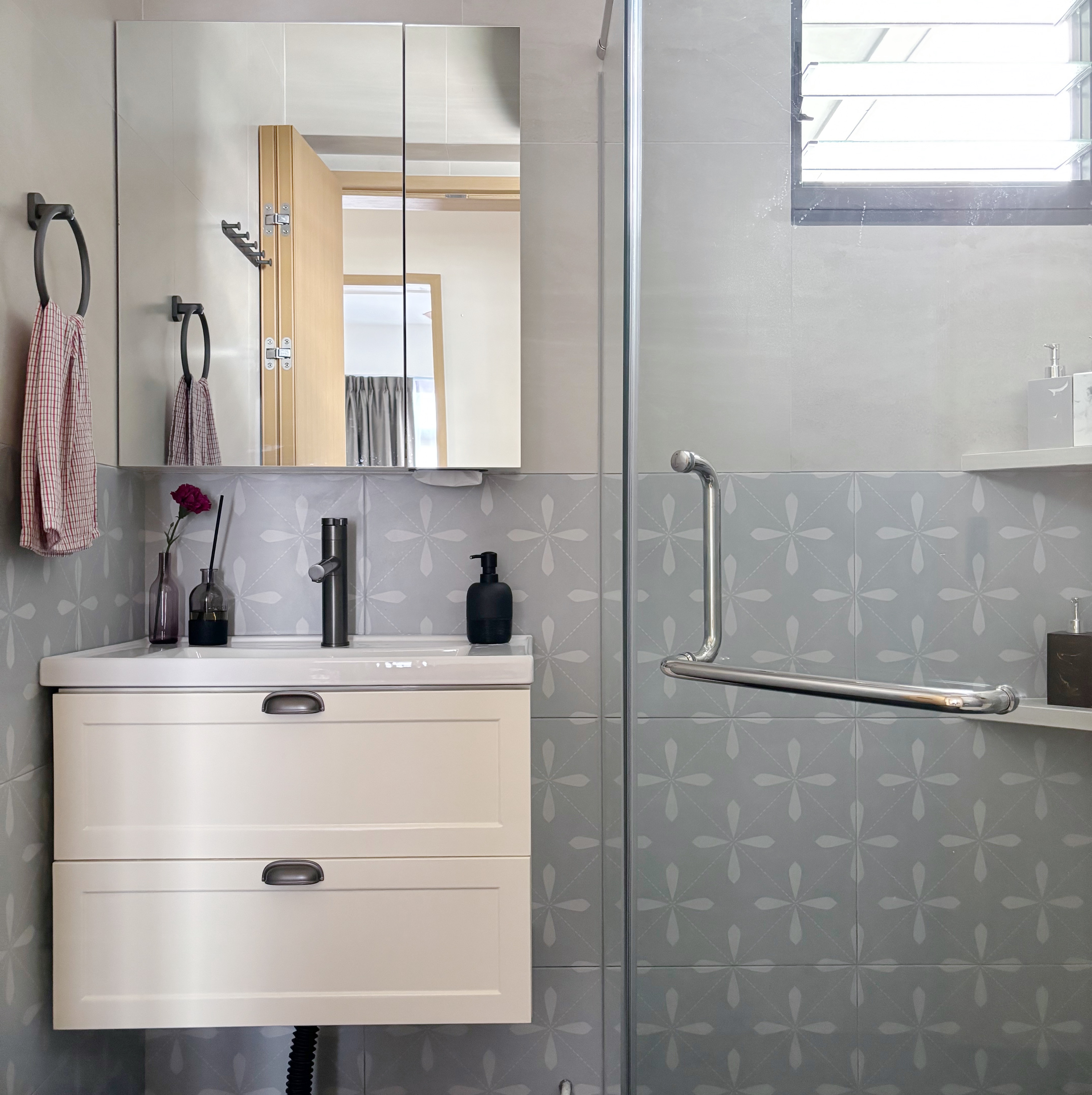 Our fun guest bath/powder room - White bathroom vanity with two drawers, black faucet, gray tiled walls with floral patterns