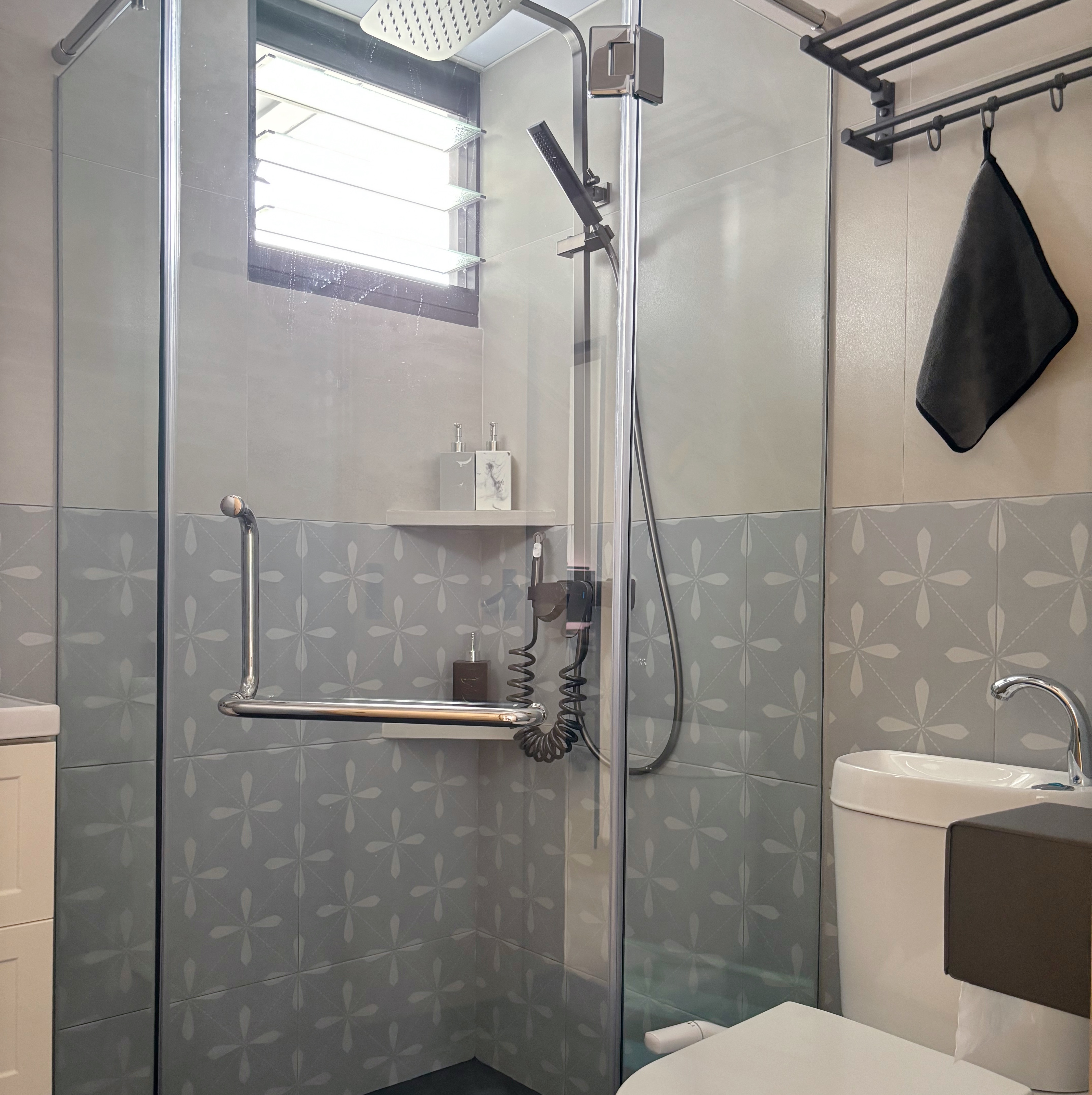 Our fun guest bath/powder room - Glass shower enclosure, modern design, tiled walls, floral pattern, white sink, black