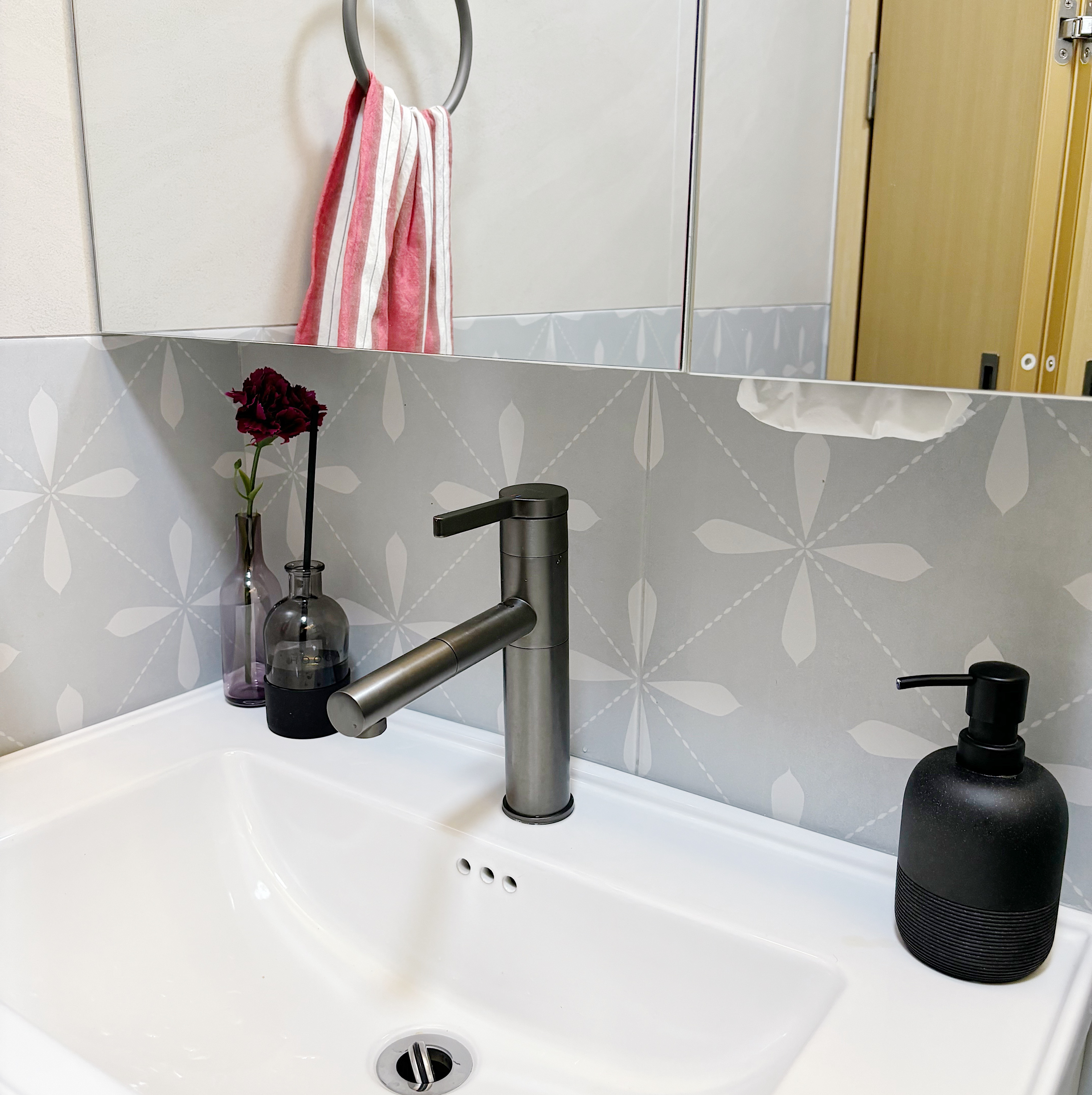 Our fun guest bath/powder room - White bathroom sink, modern faucet, gray wall tiles, red and white striped towel, vase with