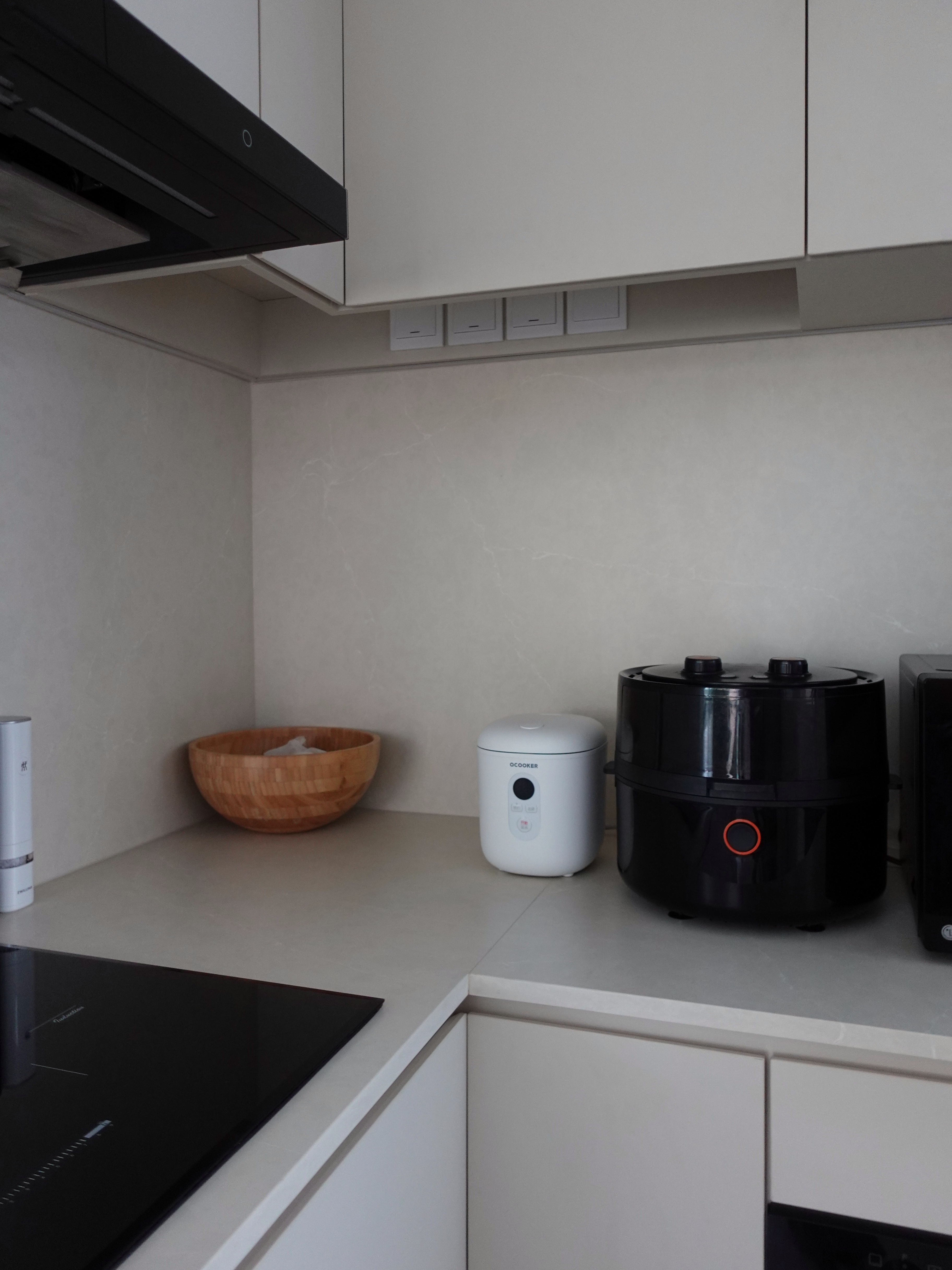 How we hid everything for a minimal kitchen - White kitchen cabinets, modern appliances, black stovetop, wooden bowl, rice