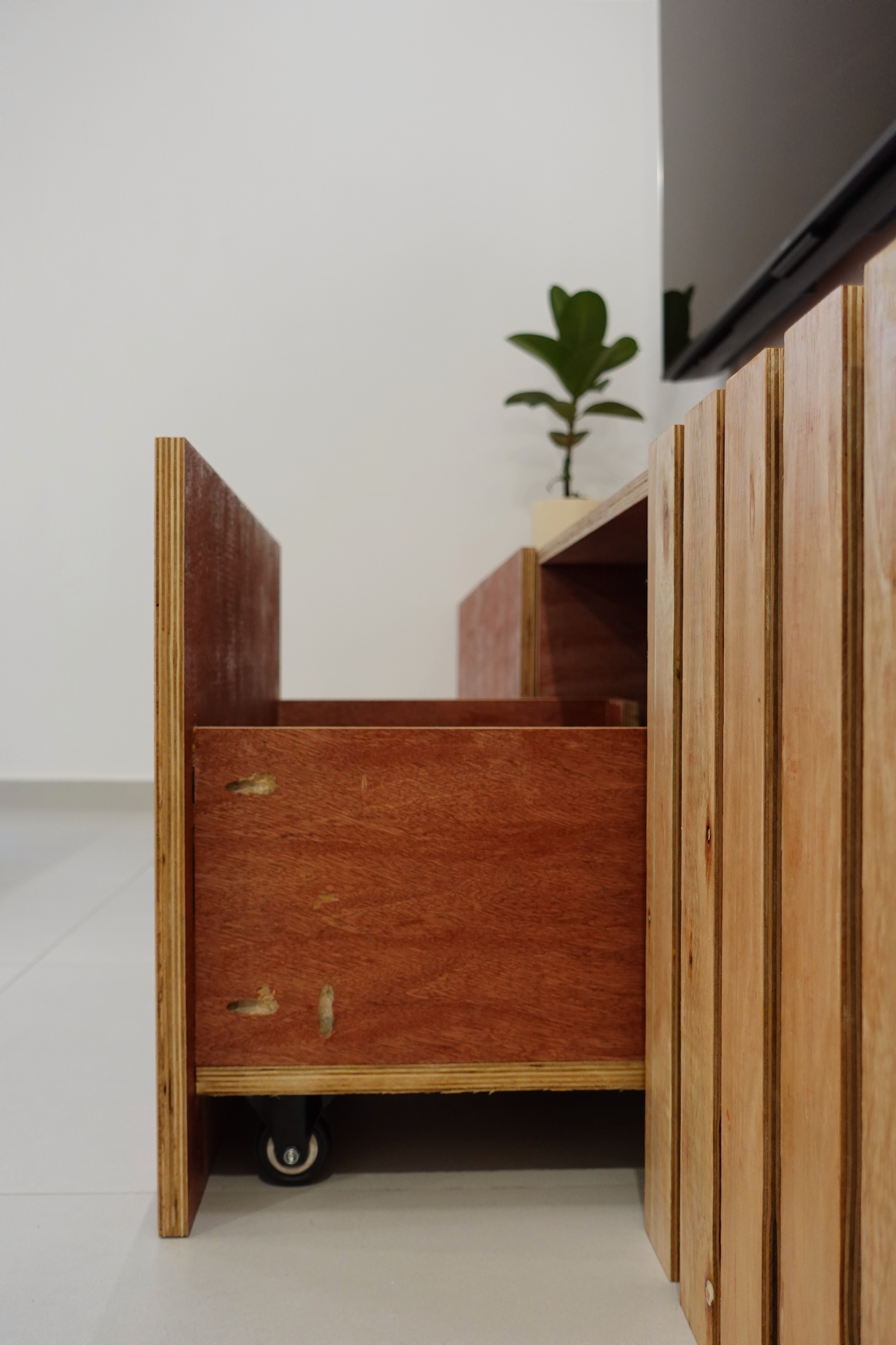 A minimal living room with a full out DIY TV console - Wooden drawer with visible scratches, small black wheels, wooden panel