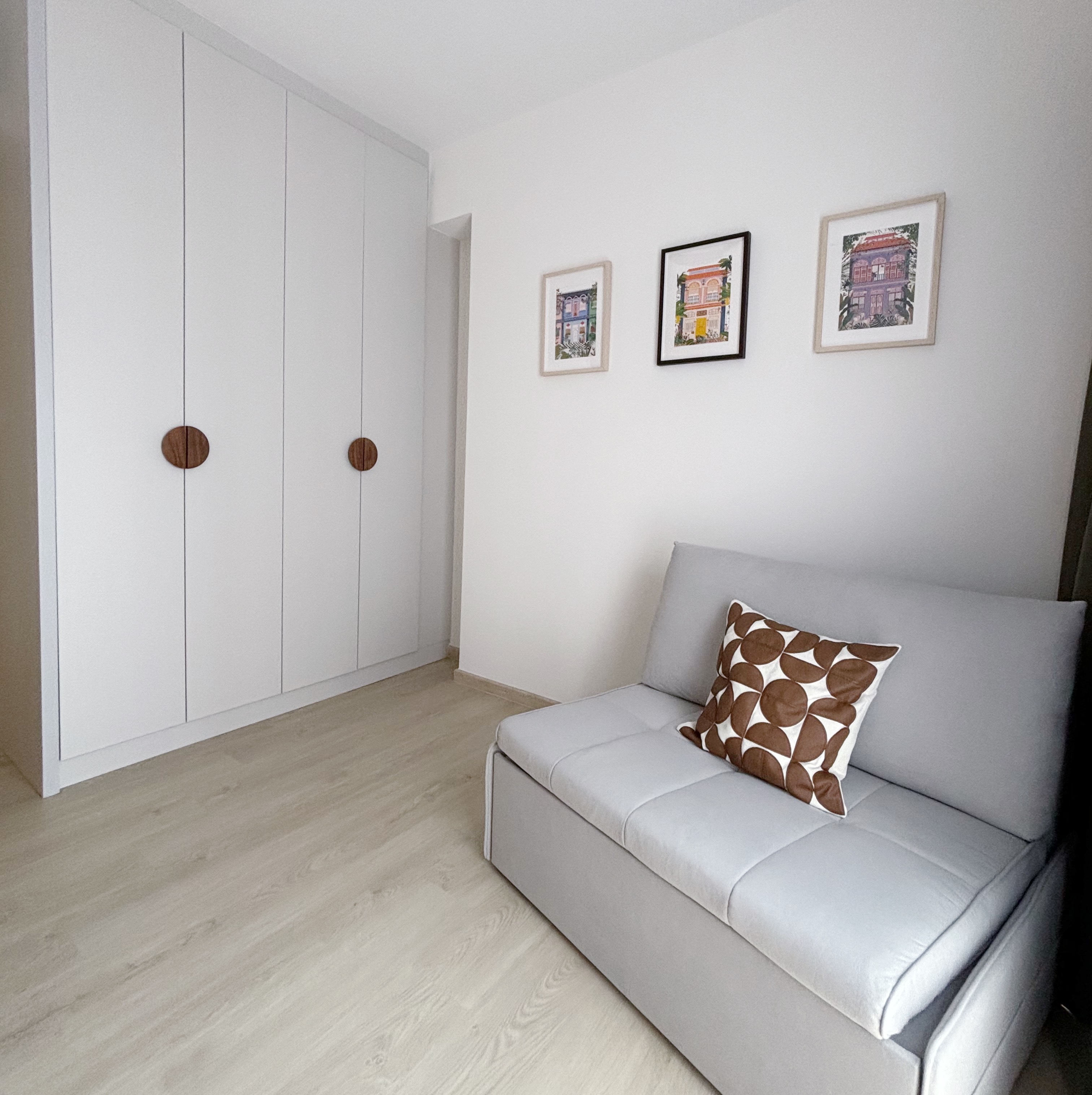Humble Cozy Guest Bedroom - White minimalist wardrobe with round wooden handles, light gray sectional sofa with brown