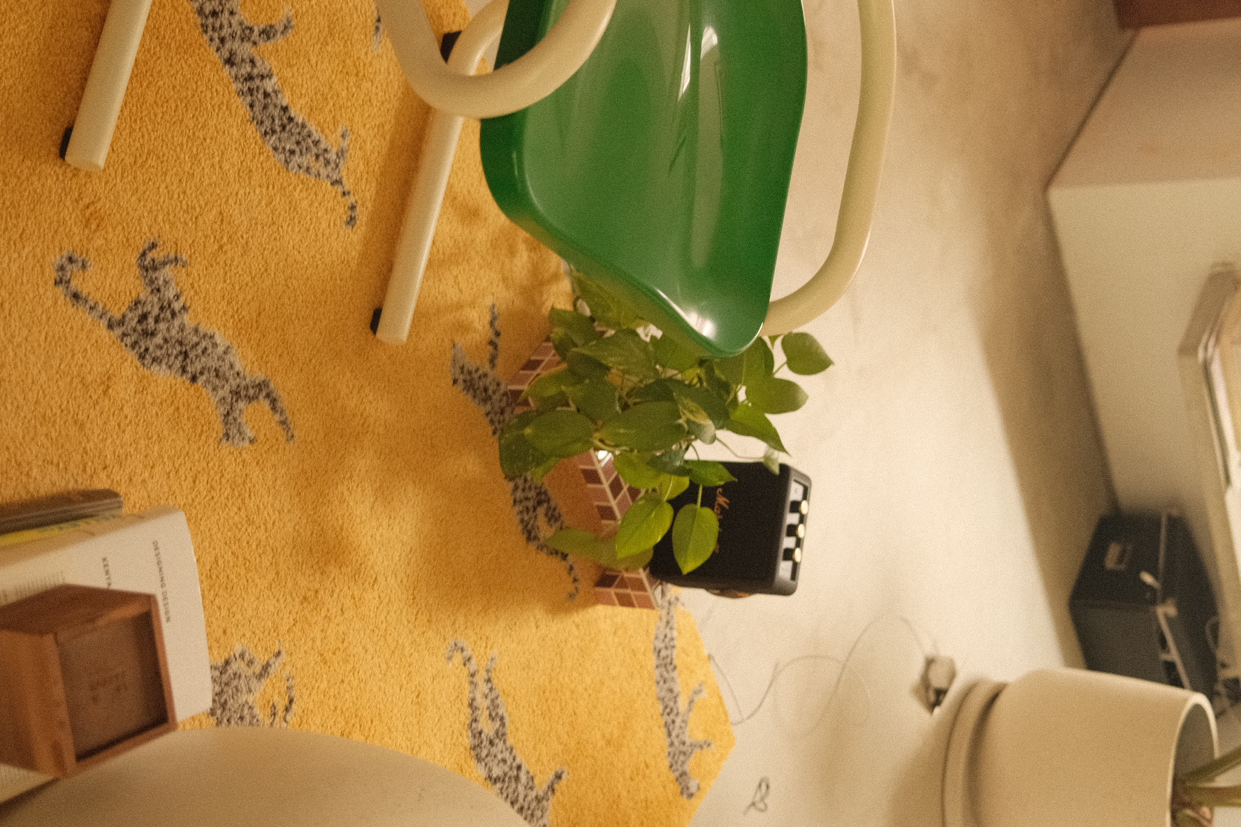 Welcome to our green sanctuary! - yellow rug with gray animal prints, green chair with white armrests, potted plant with