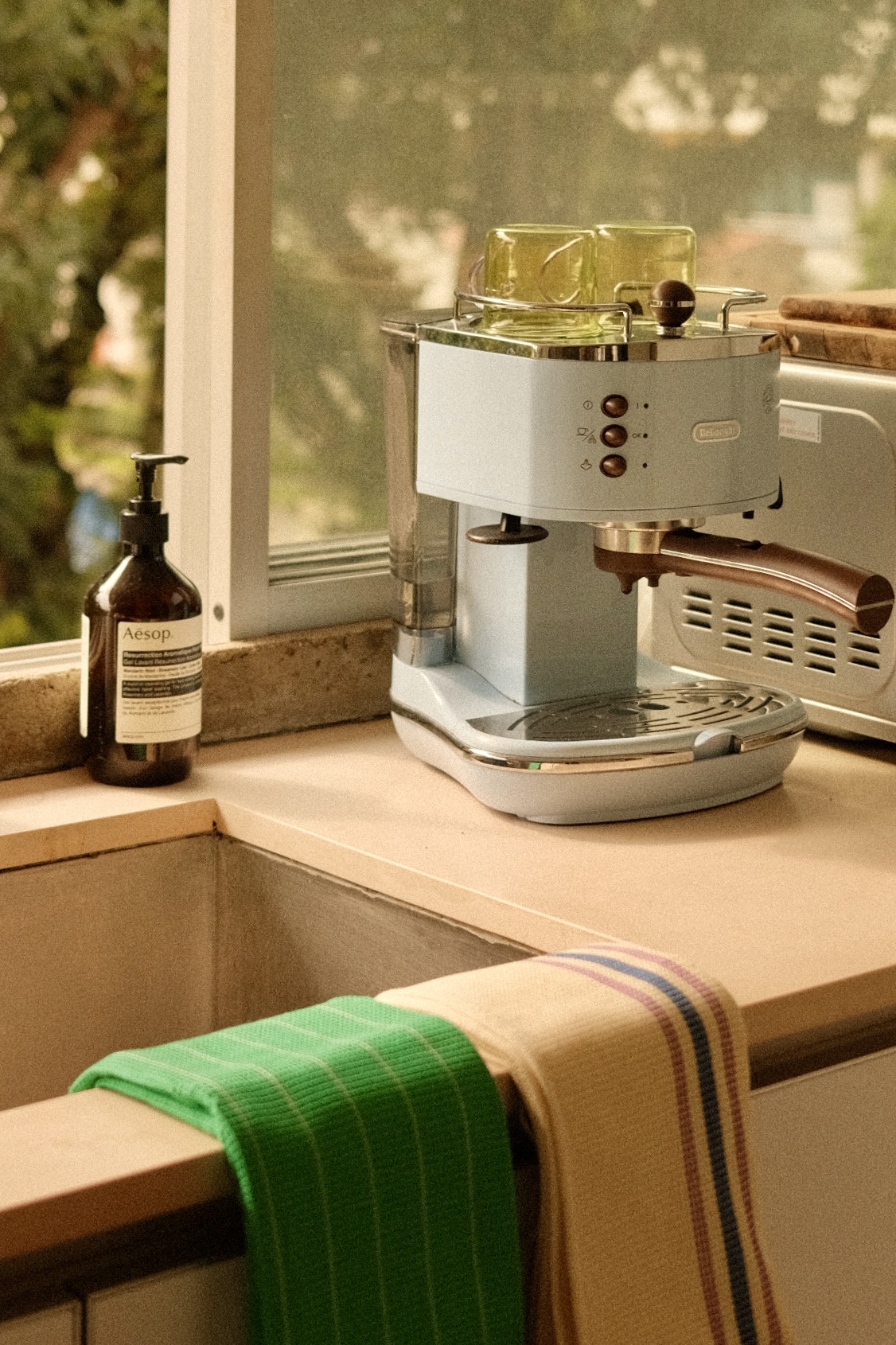 Open kitchen overlooking a green oasis! - coffee maker, espresso machine, kitchen counter, window sill, green towel