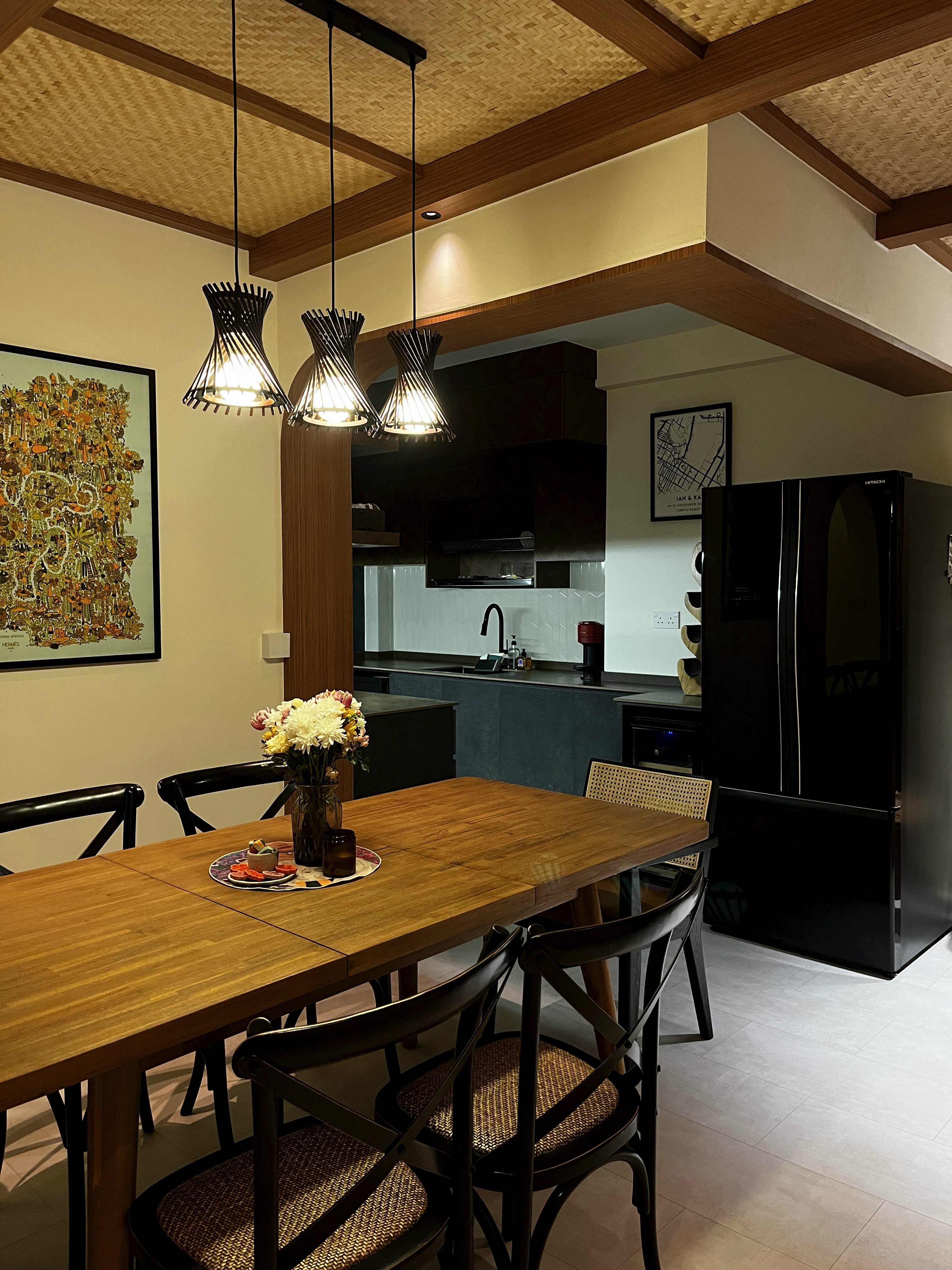 The Ultimate Hosting Guide - Modern dining room with wooden table and chairs, black refrigerator, woven chair seat, hanging