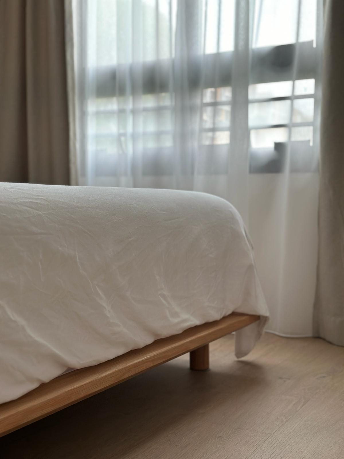Japandi and wabi-sabi master bedroom  - White bed with wooden frame, sheer curtains, natural light, minimalist decor, cozy
