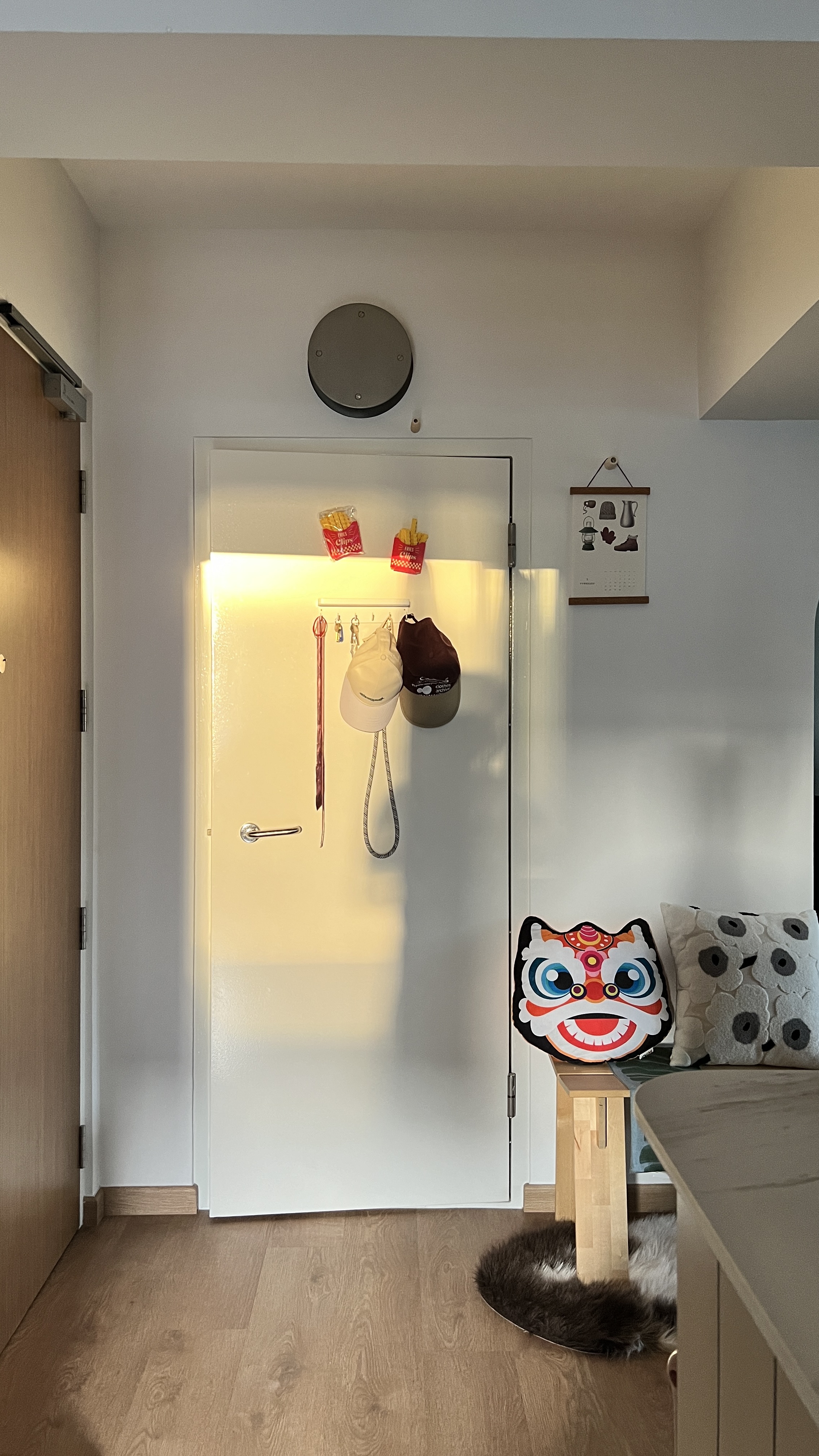 The entry way to wonders - doorway, closet, hooks, hats, bag, calendar, light, wooden floor, bed, pillow, decorative pillow