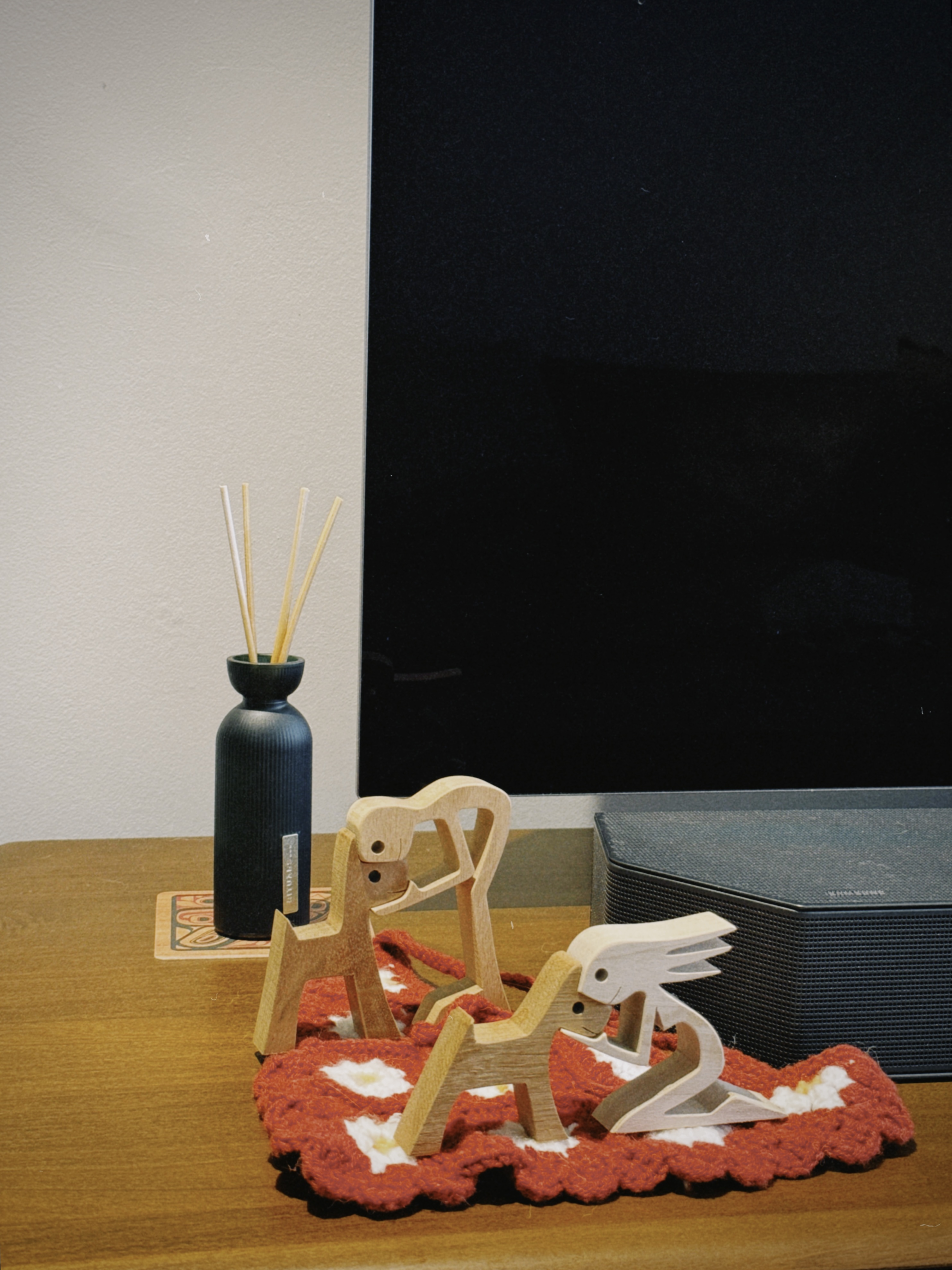 A Mid-Century Modern Home with Wood, Warmth and Colours - Wooden animal figurines, red and white crocheted blanket, black