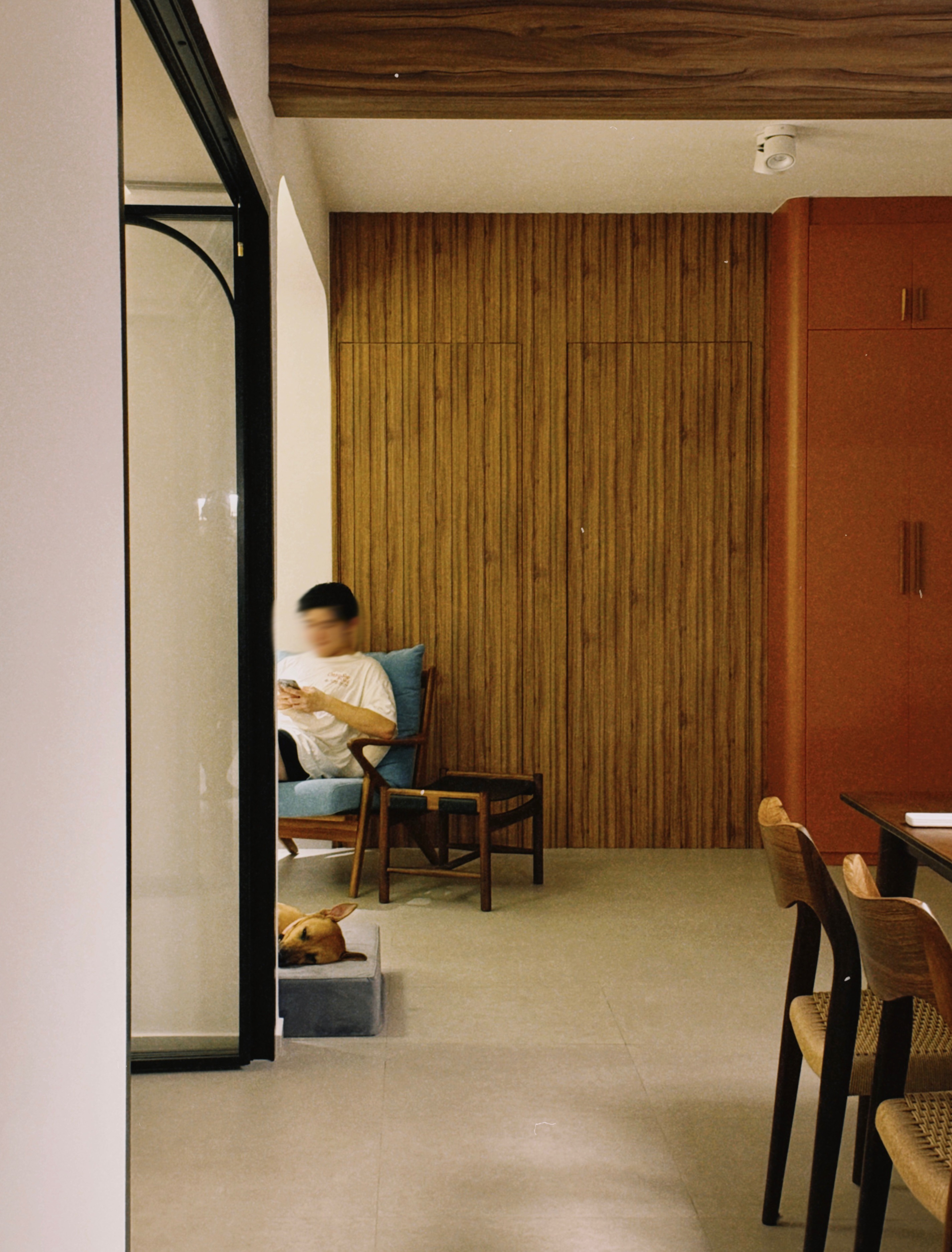 A Mid-Century Modern Home with Wood, Warmth and Colours - Wooden wall, modern interior, person using phone, blue chair