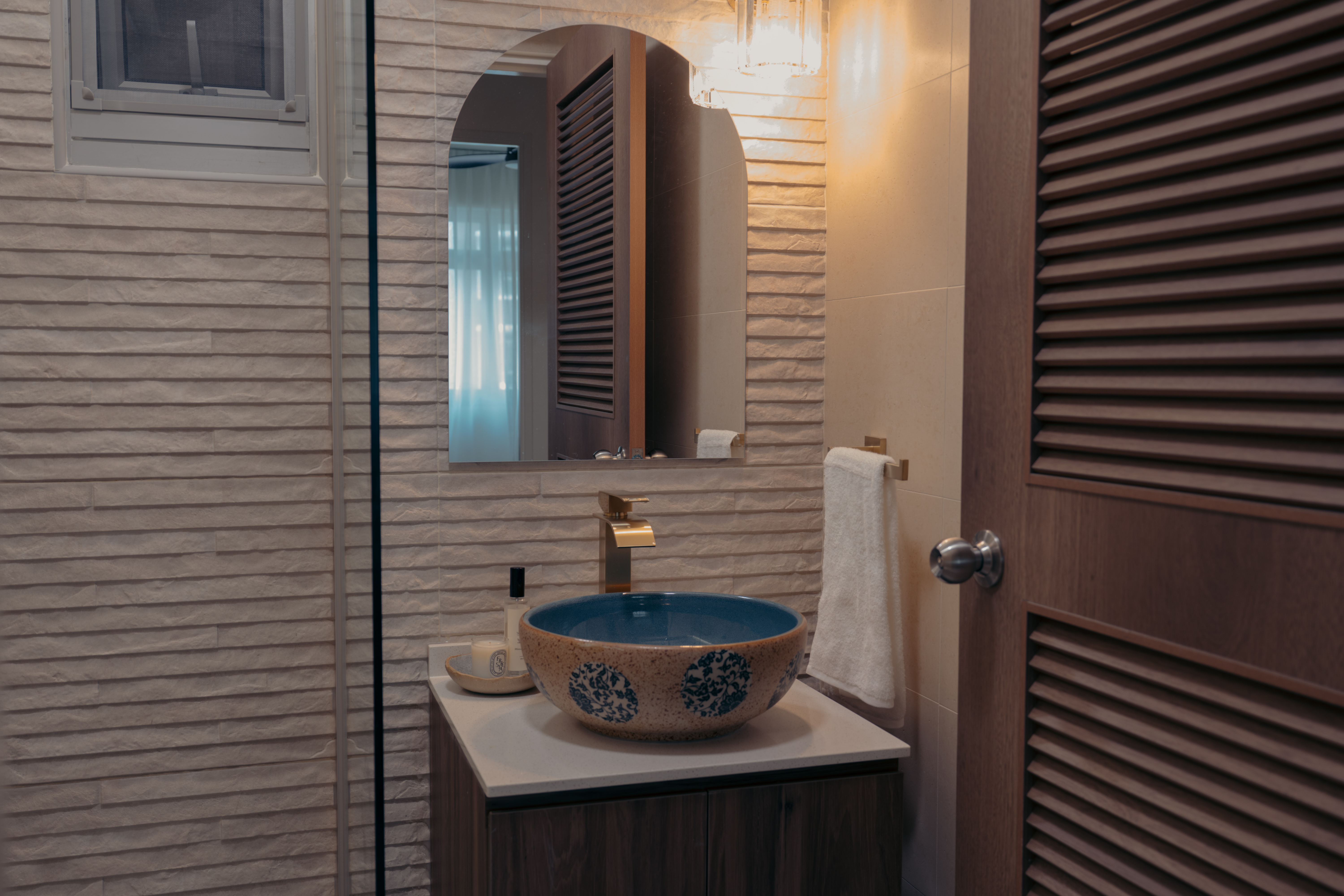 One Resort Villa Style, Two Iconic Bathrooms - Bathroom vanity with blue patterned basin, wooden door with louvred panels