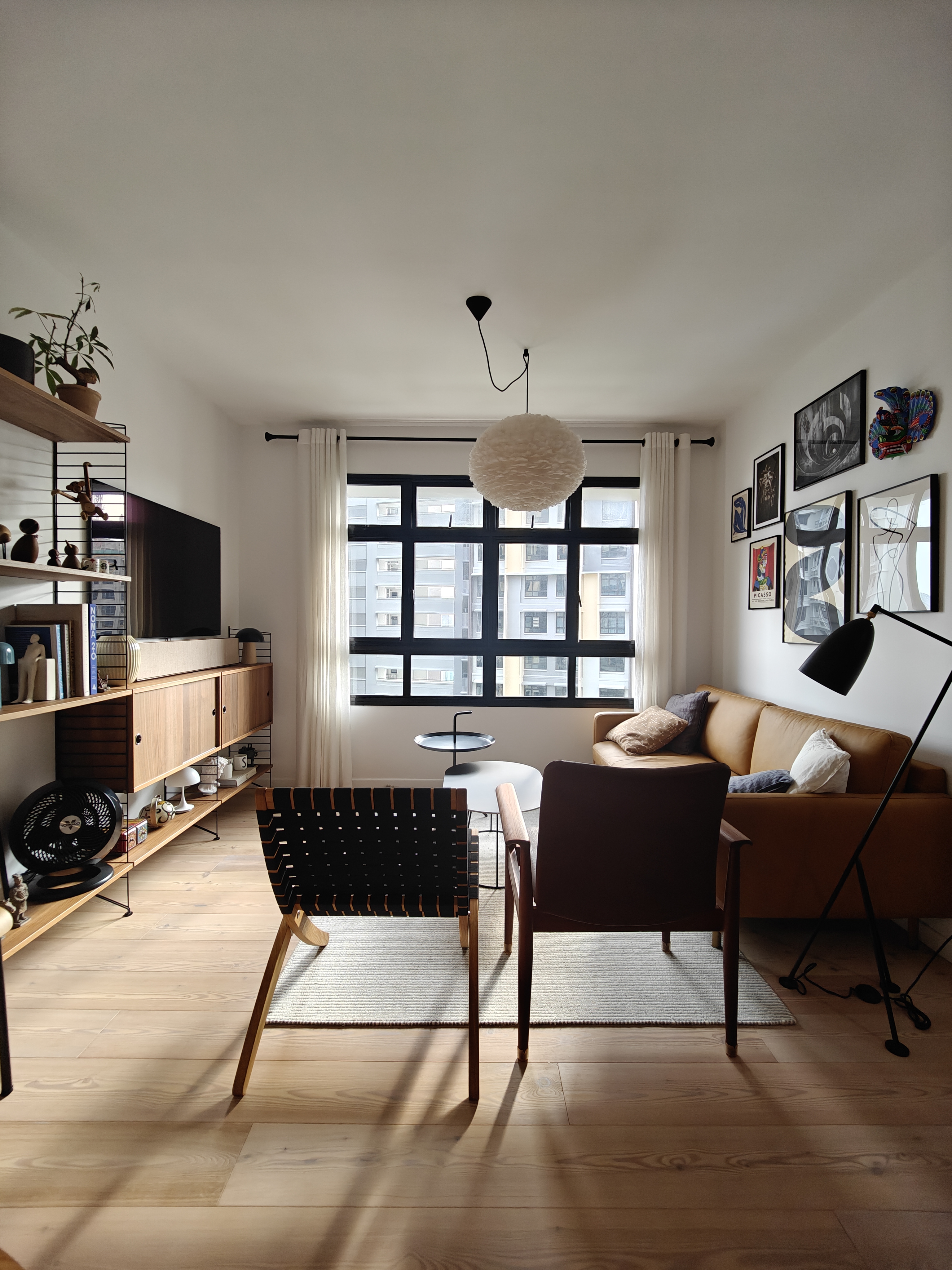 A 3-Gen Scandinavian Home - Modern living room, cozy seating, minimalist decor, large window, natural light, wooden shelves