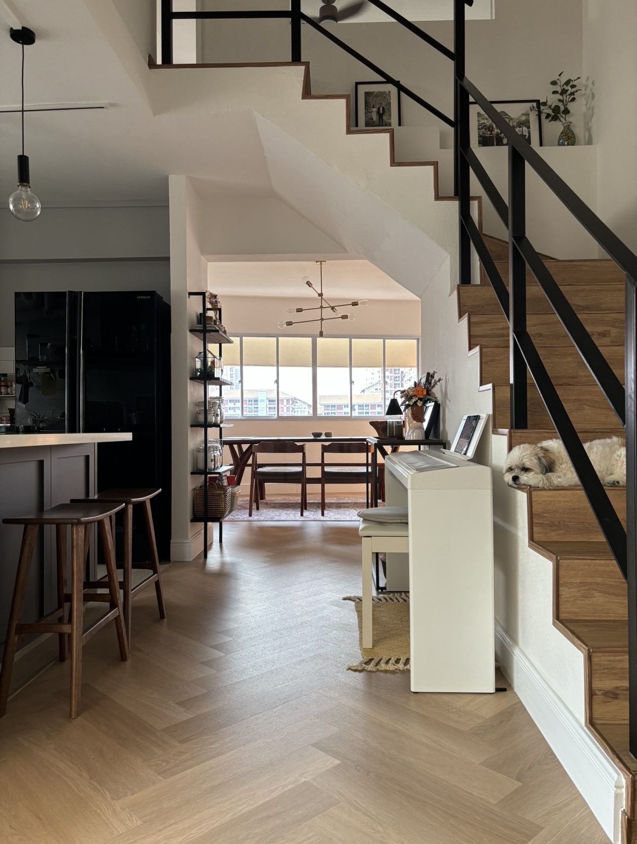 Warm & Cosy HDB Maisonette - Modern kitchen with black appliances, wooden dining table and chairs, large windows with city