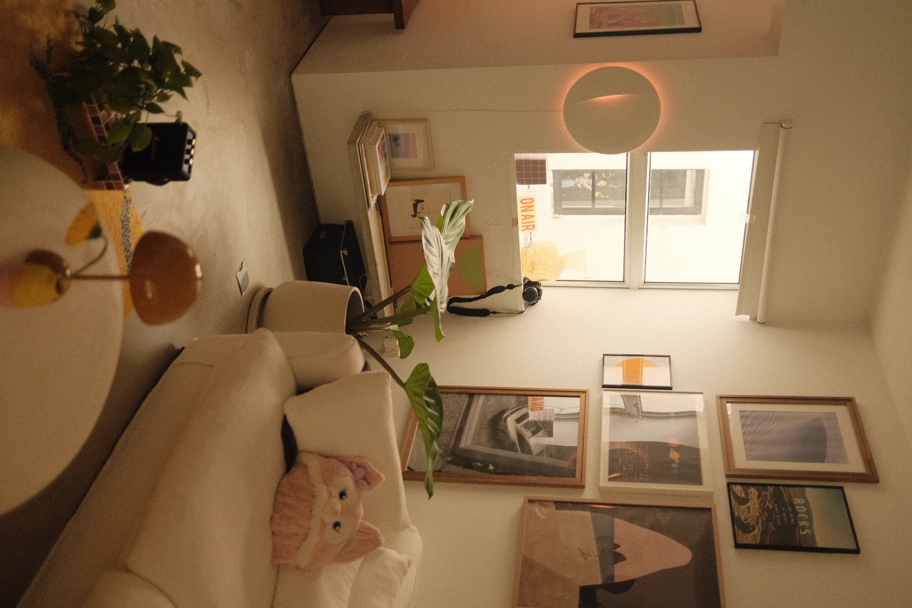 Our cozy corner in an eclectic home - Couch with plush toy, framed pictures on wall, indoor plant, warm lighting, abstract