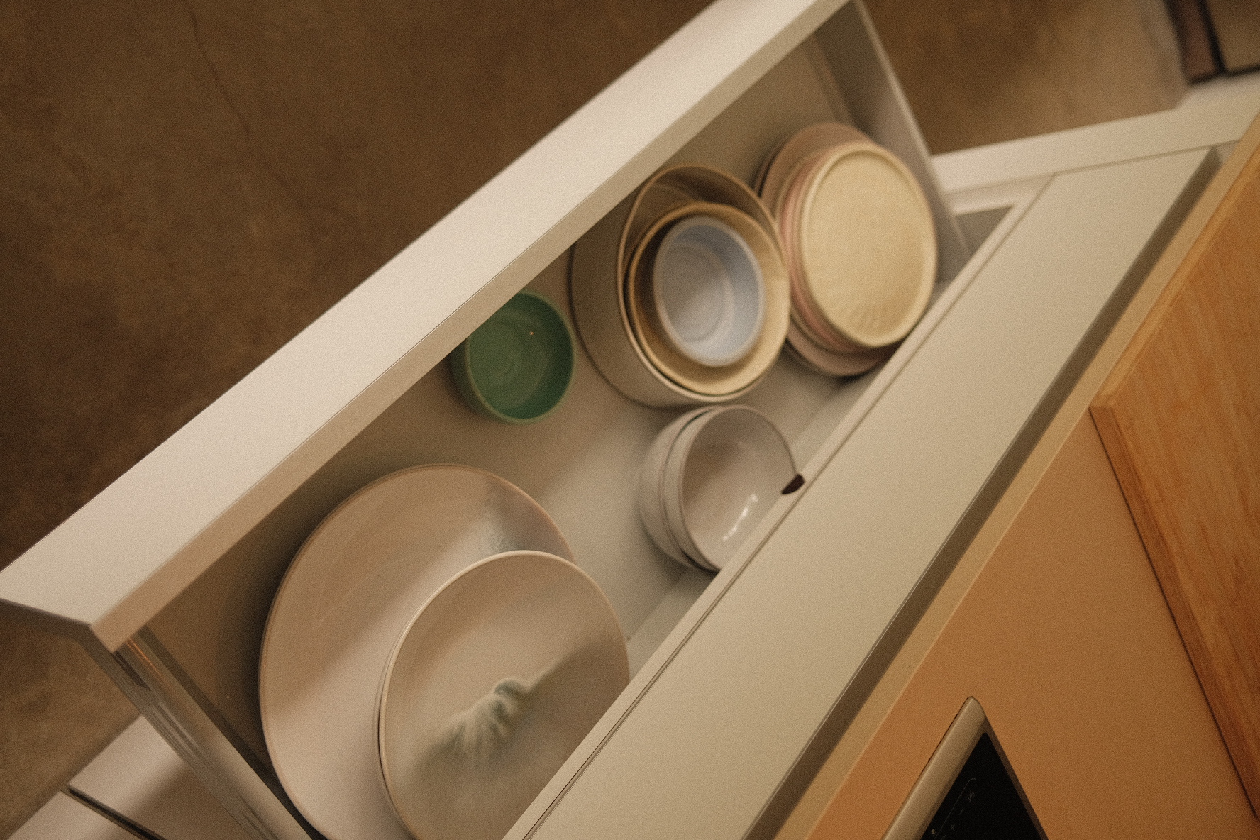 Kitchen Organisation around our Island Kitchen - White kitchen drawer, neatly organized dishes, beige and green bowls, wooden