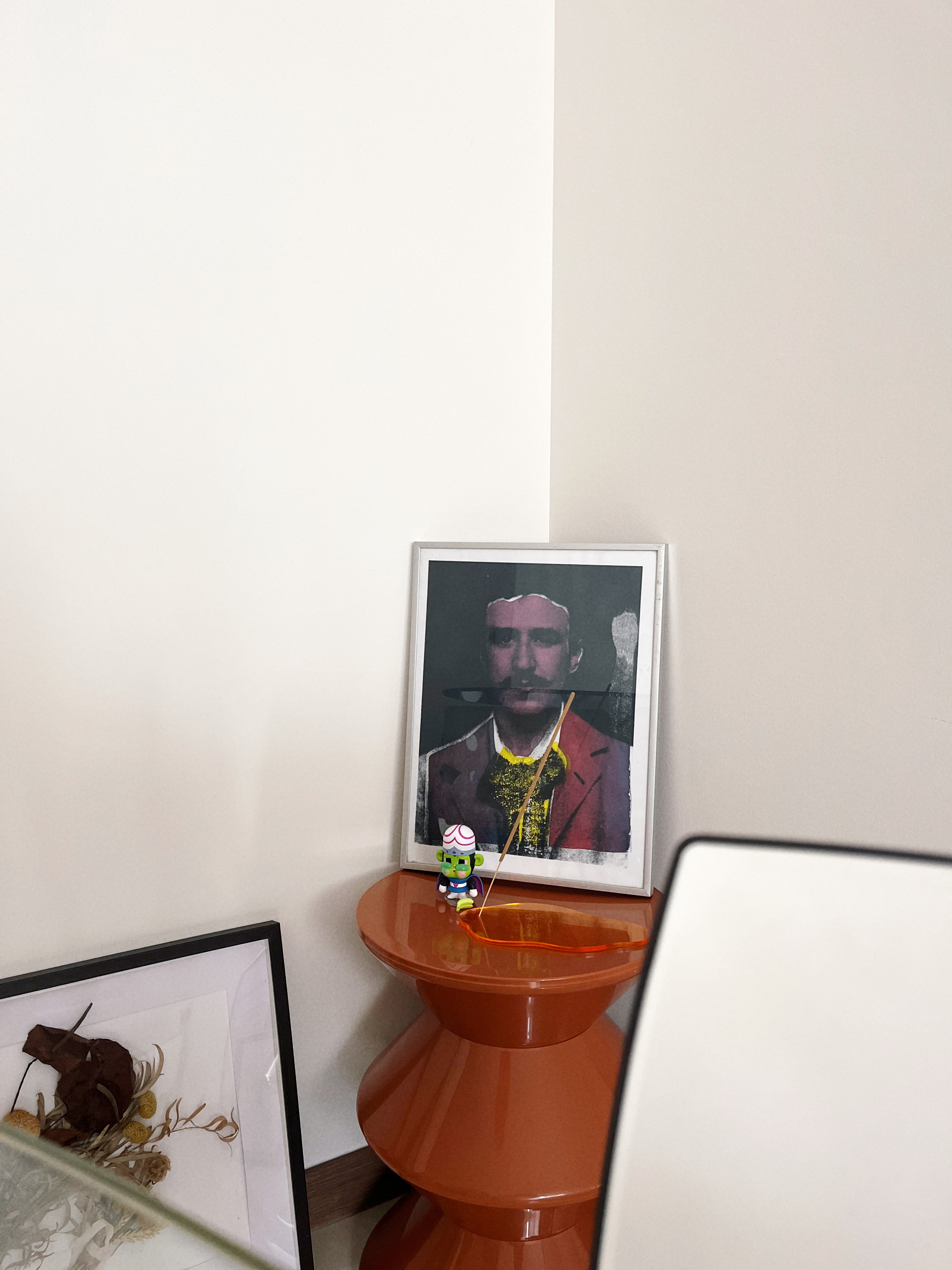 Come dine with beaconstrips: A space filled with mismatched chairs - Orange side table with framed portrait and small green