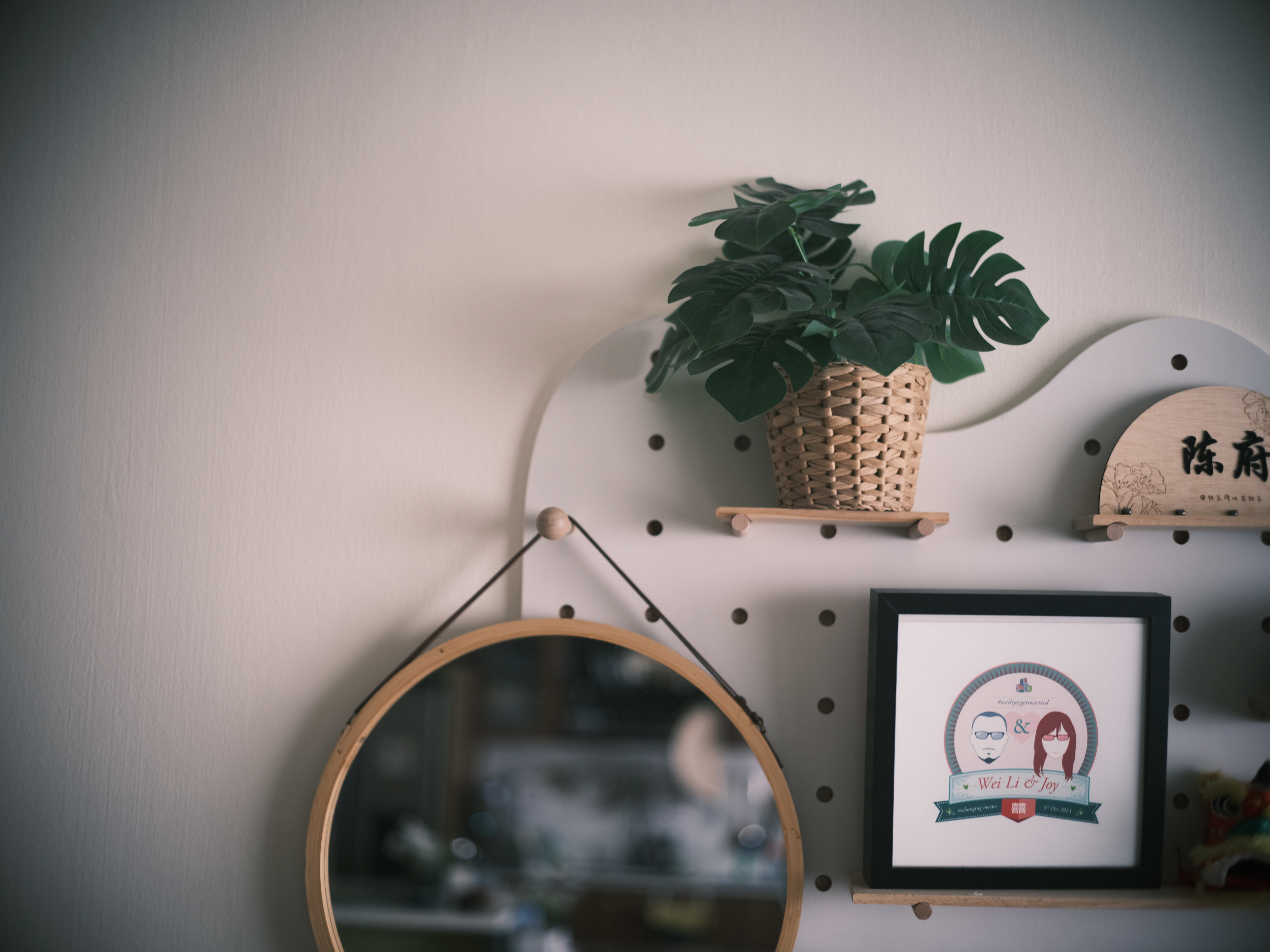 An entryway built around family habits - Woven plant pot, wooden shelf, circular mirror, framed photo, decorative wall art