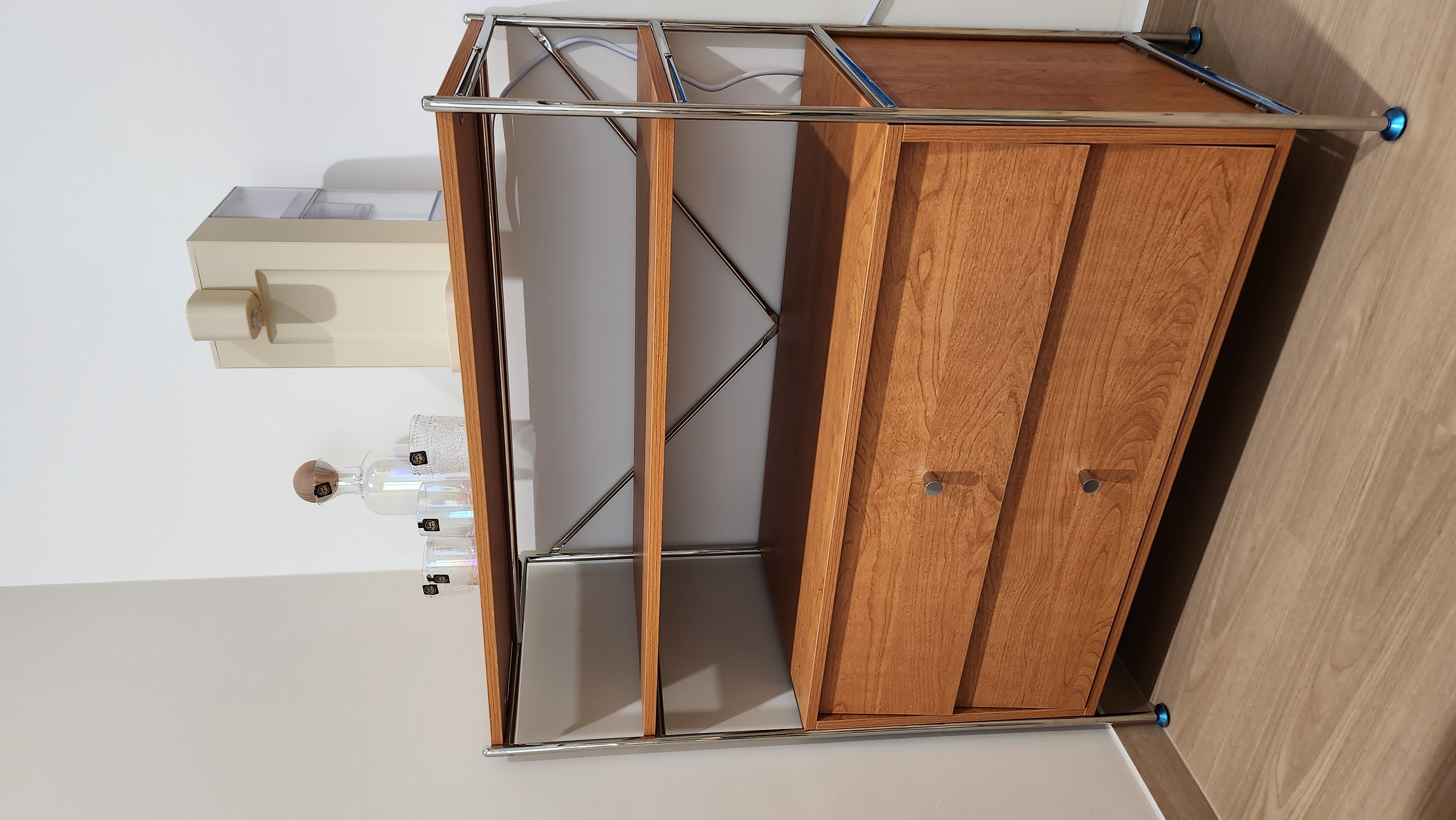 Minimalist Monopoly.home - Wooden cabinet with metal frame, glass shelf, blue knob, white wall, light beige floor, wooden