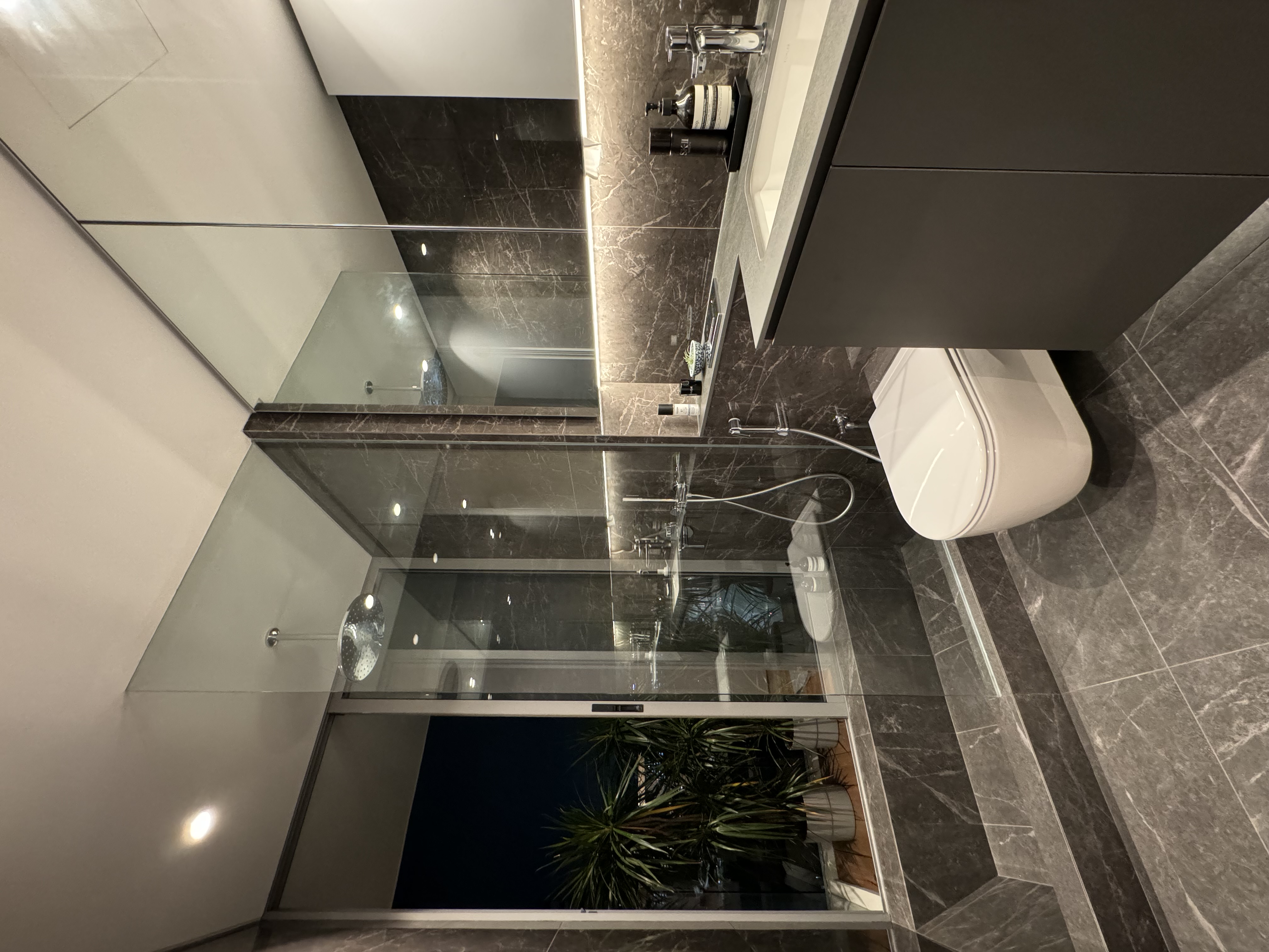 Rumah Beacon, where each object tells a story. - modern bathroom, sleek design, high-end fixtures, dark marble tiles, glass