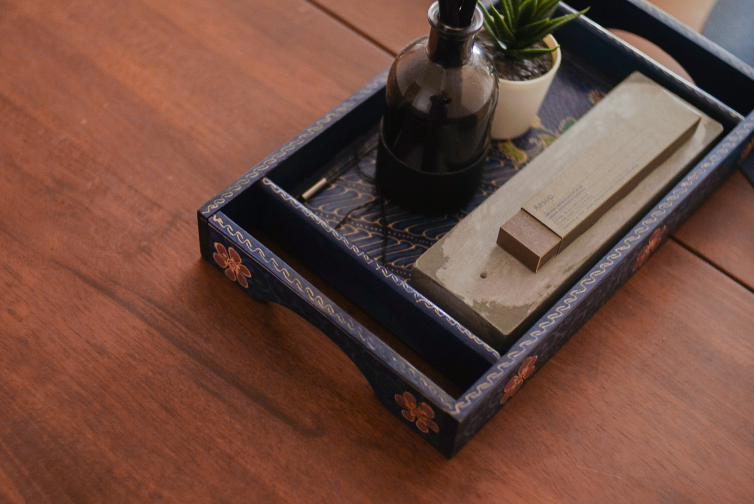 Invite Eat! — Break fast with us - Dark blue tray, intricate design, wooden surface, small potted plant, rectangular box